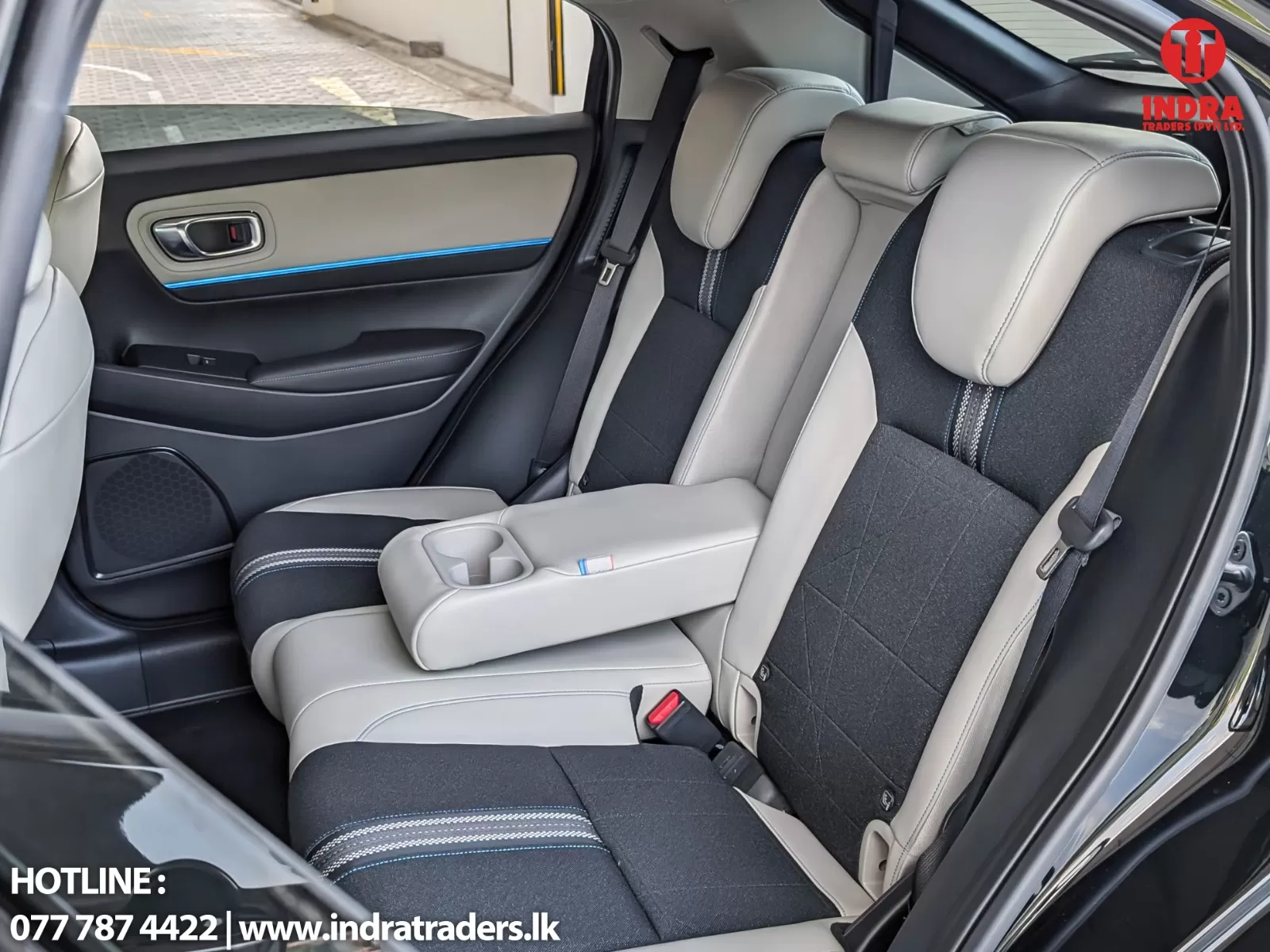 Rear row of a car with beige leather seats, center armrest containing cup holders, and blue door accent lighting on the panel.