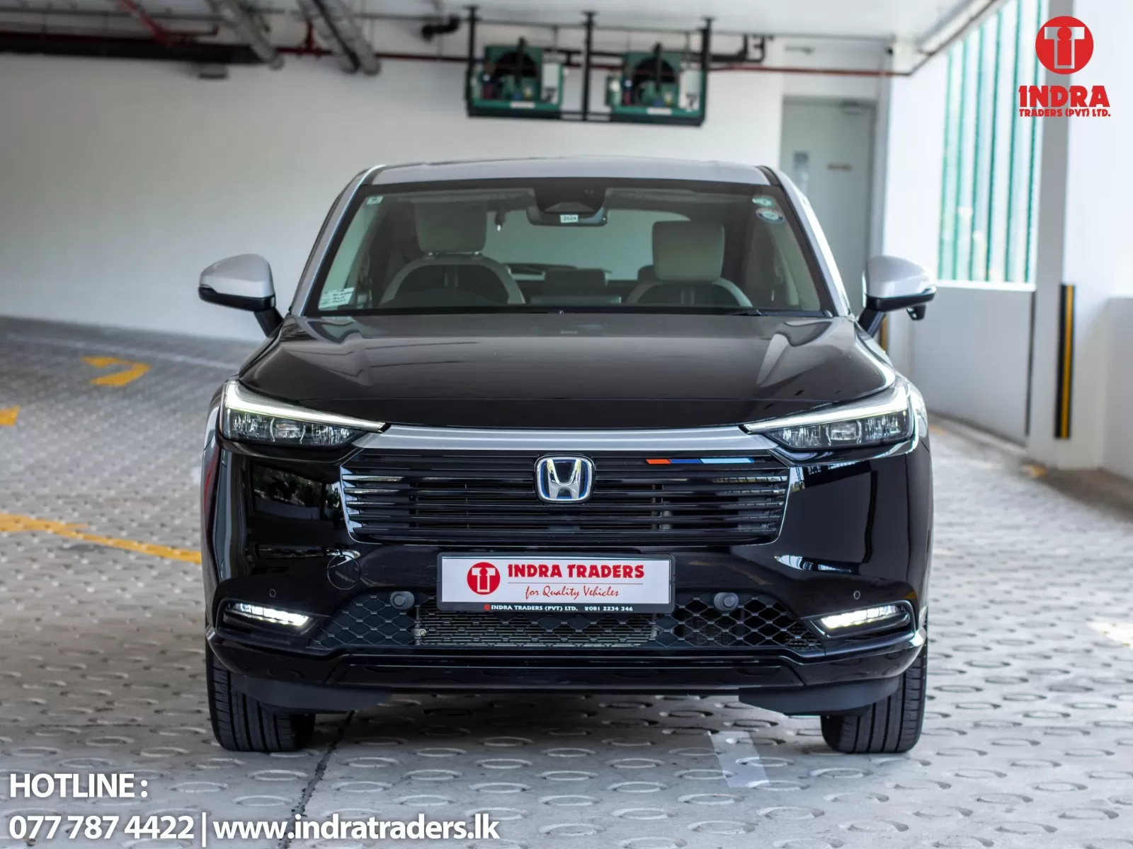 Front view of a black Honda SUV in an indoor showroom with Indra Traders branding in the corner.