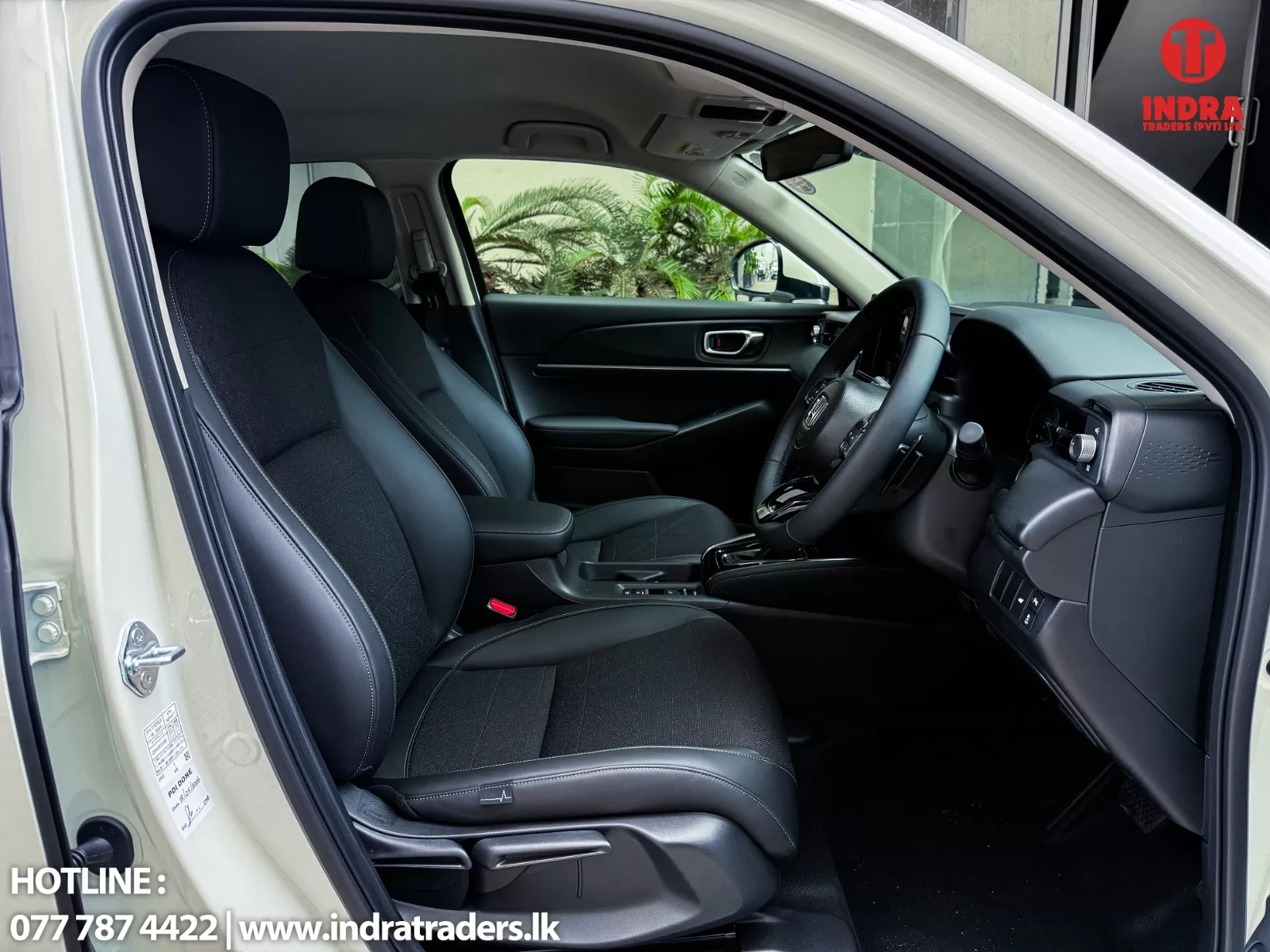Interior of a modern car with black fabric seats, steering wheel, and center console seen from the open front door edge.