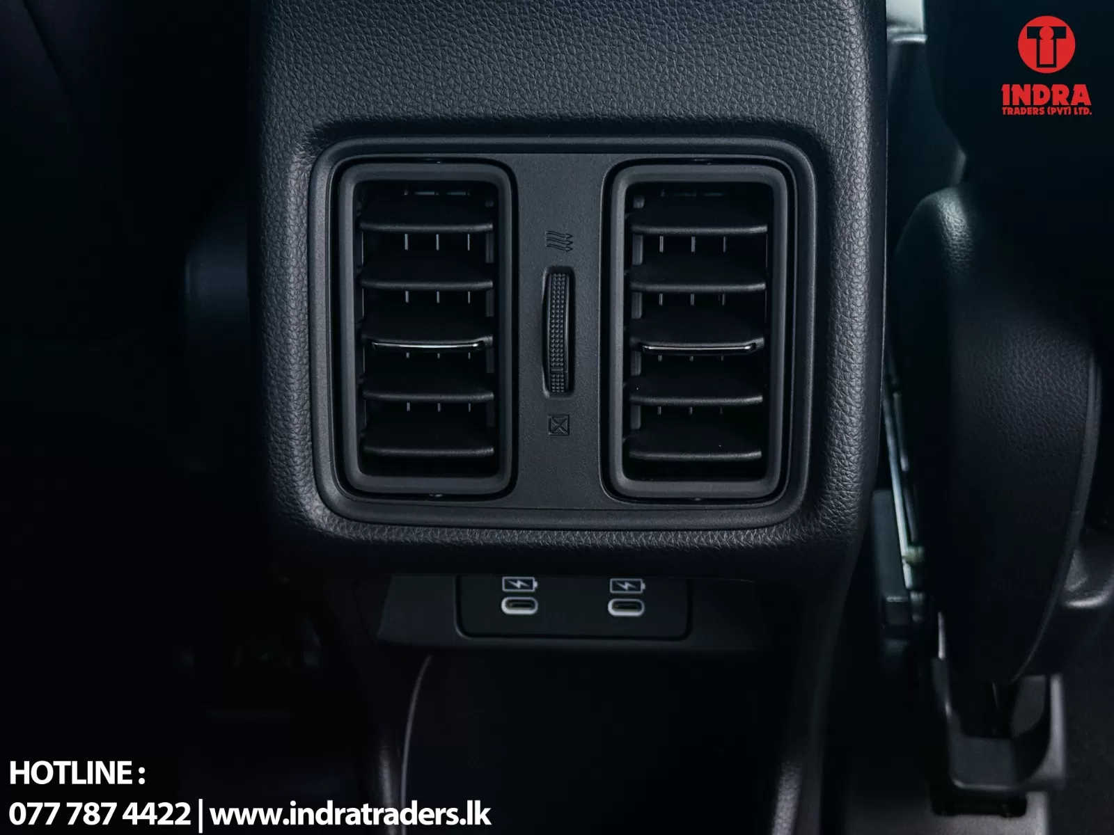 Rear air conditioning vents in a car center console with a vertical slider between them and textured black trim, watermark logo in top-right corner.