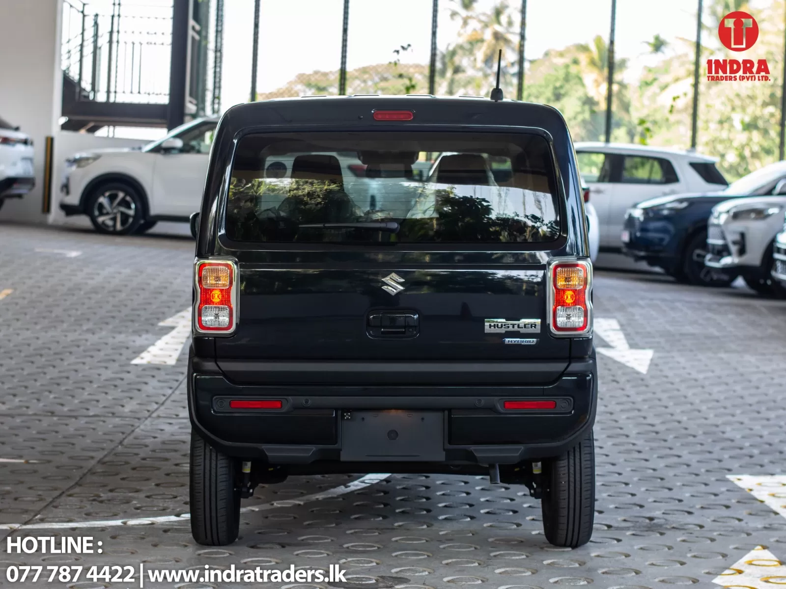 Rear view of a black Suzuki Hustler Hybrid SUV in a car showroom lot; visible dealership branding in the corner.