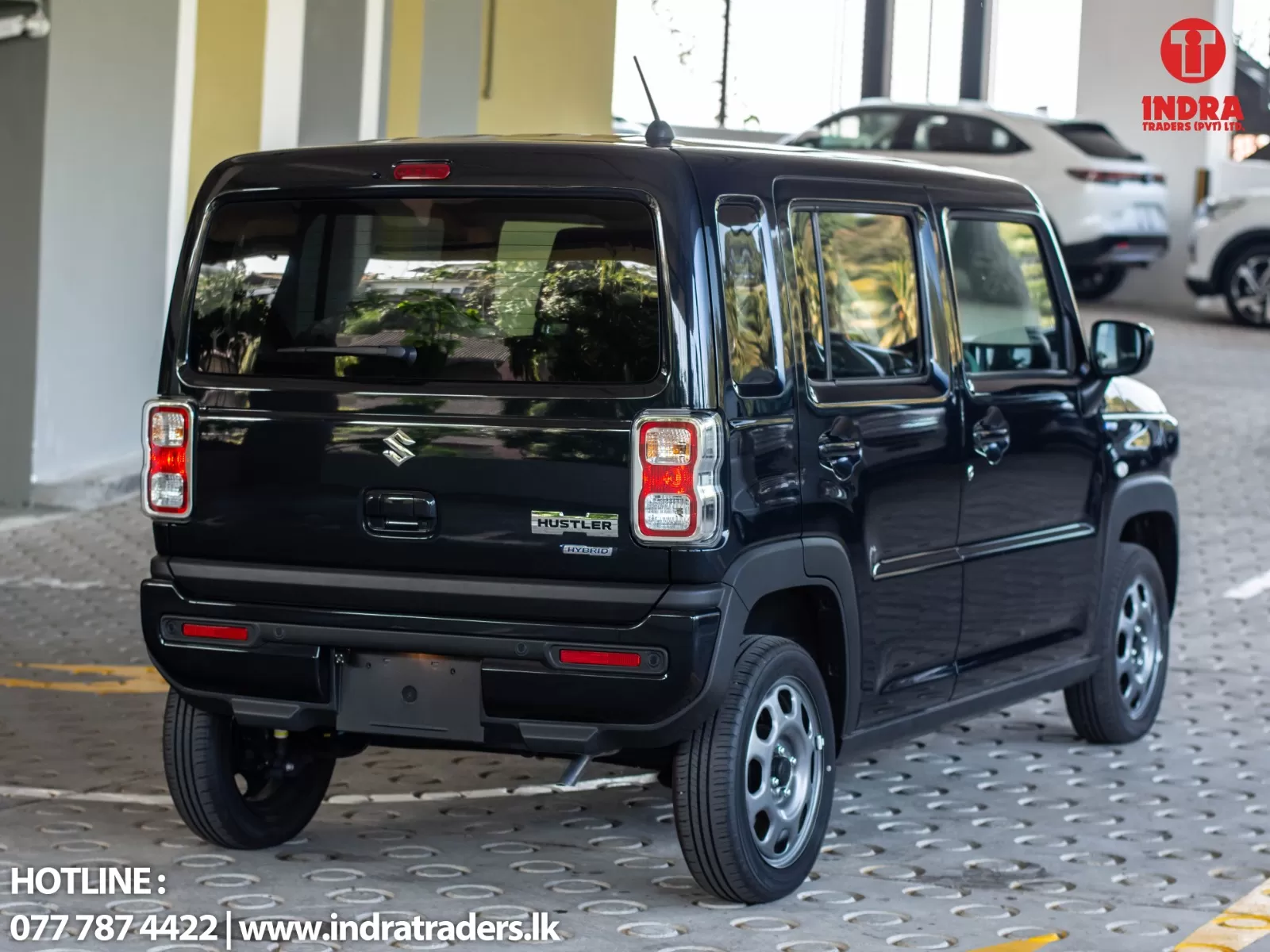 Rear three-quarter view of a black Suzuki Hustler Hybrid parked indoors, with the Indra Traders logo visible in the top-right corner.