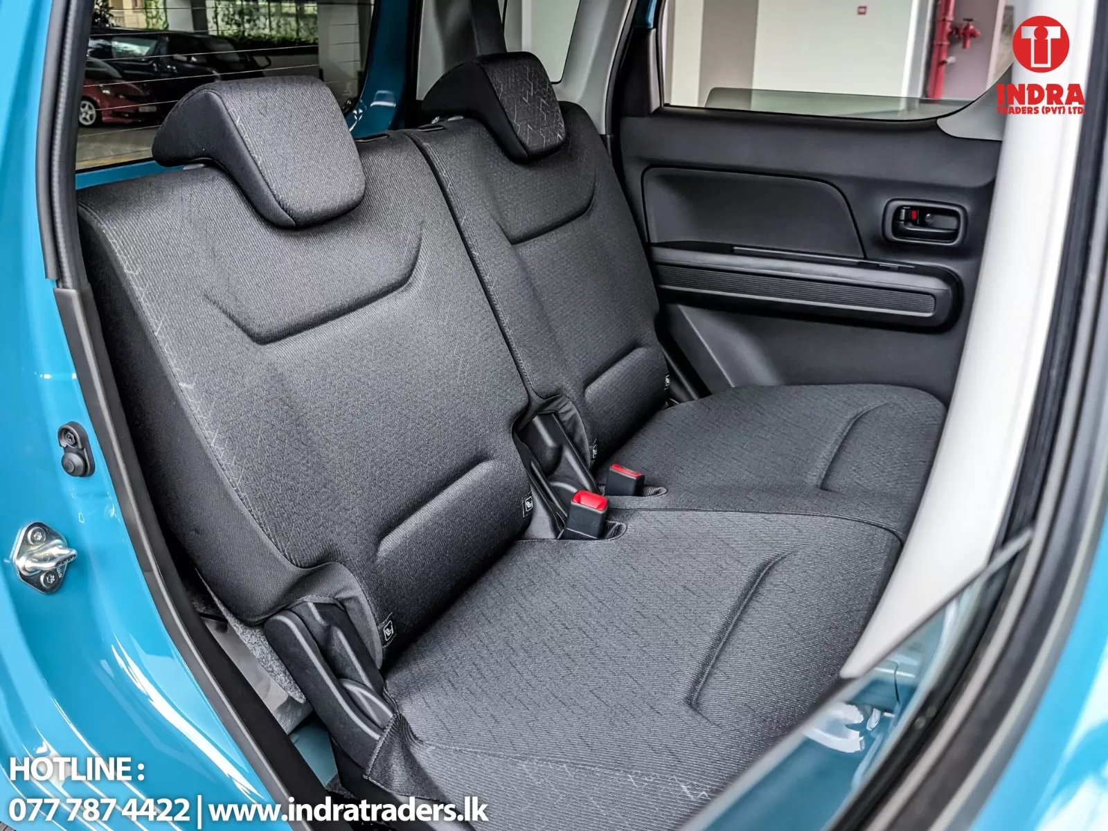 Rear seat area of a blue car with two dark gray fabric seats and headrests; door panel visible on the right, watermark with contact info at bottom left.