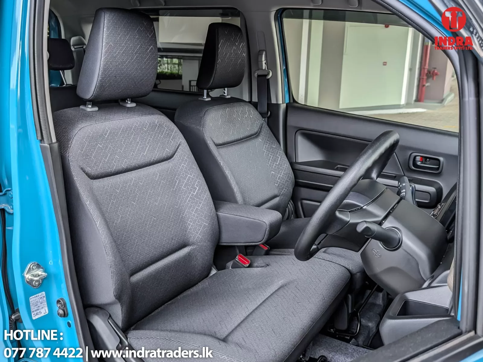 Blue compact car interior: two front seats, steering wheel, and driver's door panel visible from the open front passenger side; exterior blue color shows at the frame.