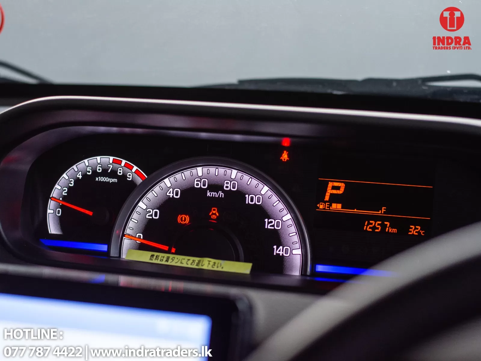 Dashboard of a car showing illuminated speedometer and tachometer with warning lights; fuel and temperature readouts visible on the side display.