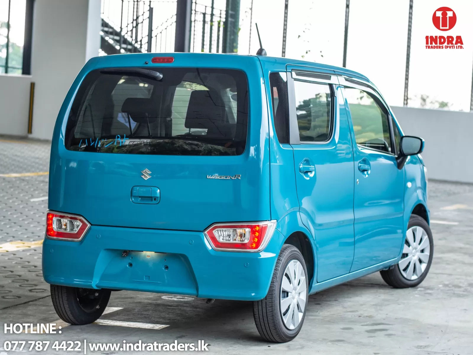 Blue Suzuki WagonR seen from the rear-left in a parking area; Indra Traders logo in the top-right corner, and contact text at bottom-left.