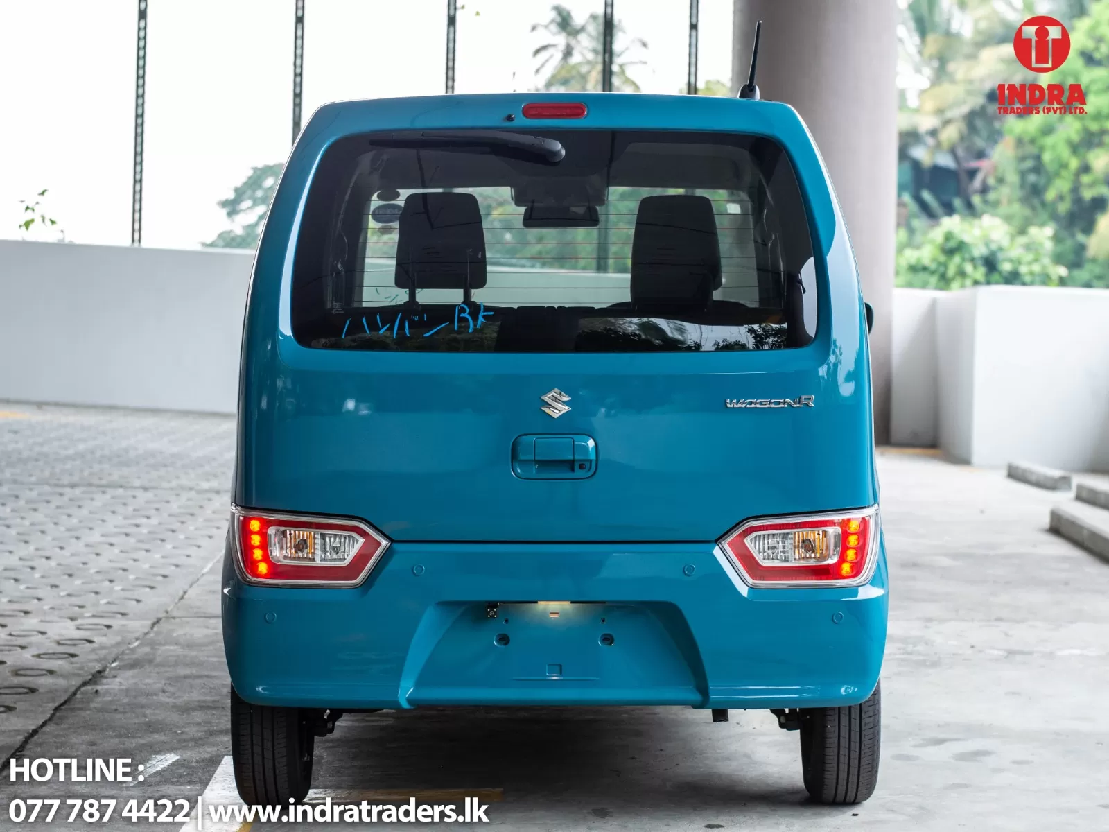 Rear of a blue Suzuki WagonR in a parking area; Indra Traders logo top-right and contact info bottom-left.