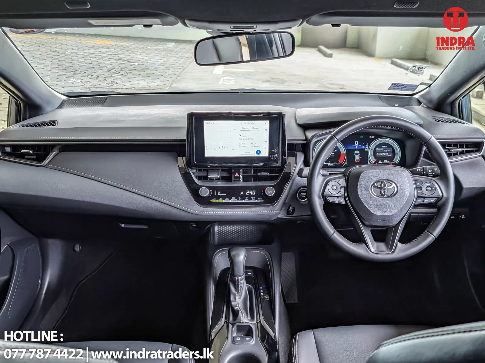 Interior view of a car dashboard with a central touchscreen, gauges, steering wheel, and gear selector