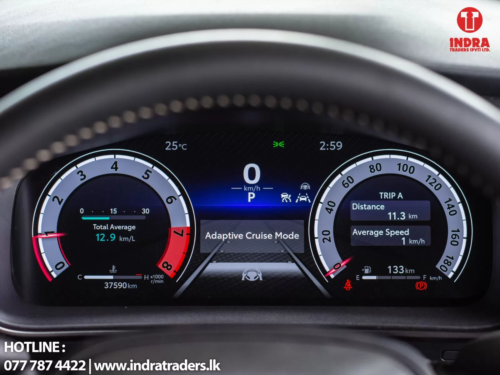 Car dashboard digital instrument cluster showing speed 0 km/h, gear P, and Adaptive Cruise Mode with Trip A displaying distance 11.3 km and average speed 1 km/h; Indra Traders logo in corner.