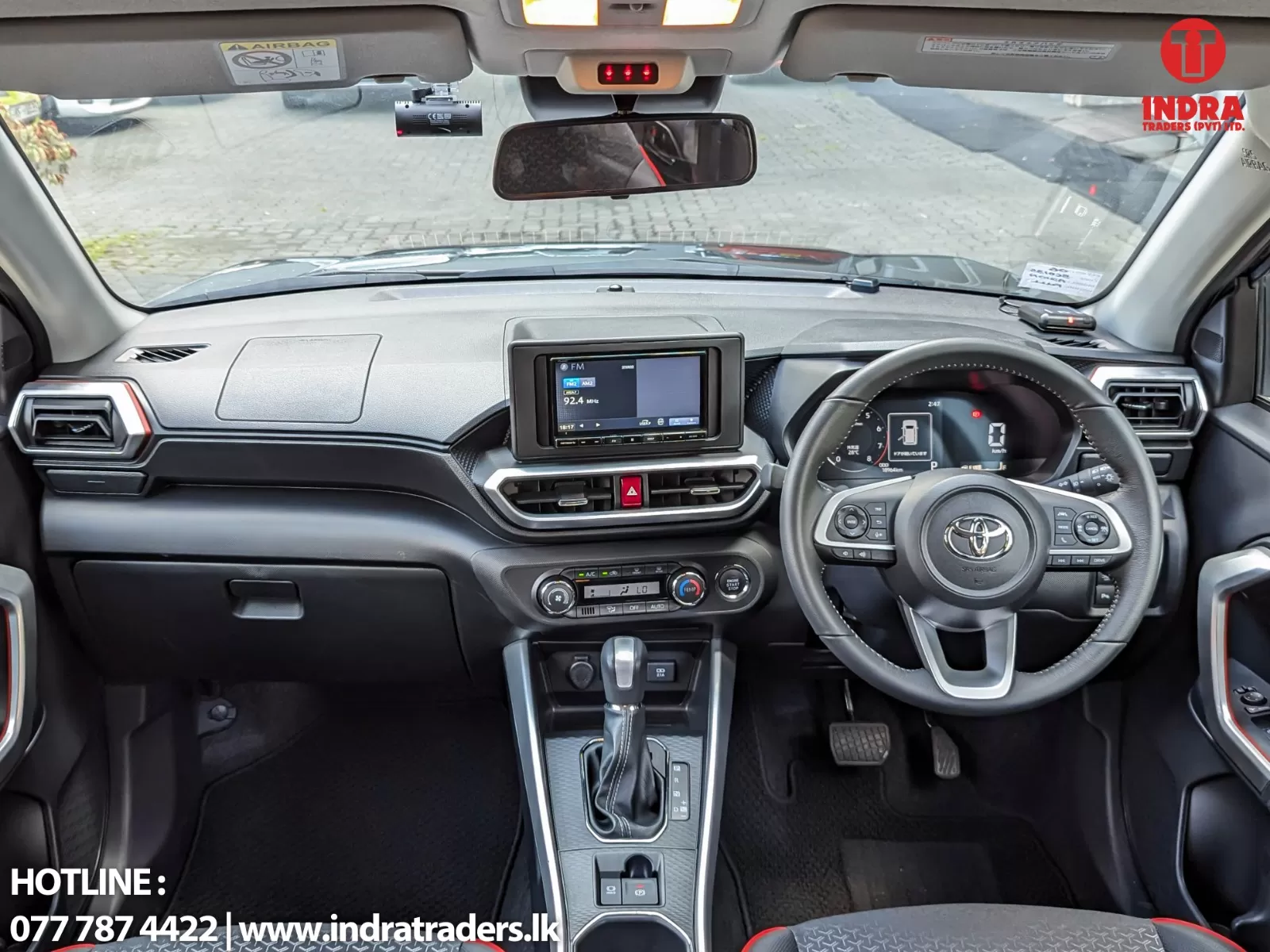 Car cockpit interior with a central touchscreen, climate controls, and gear shifter visible from the driver’s seat, front view of the dashboard.