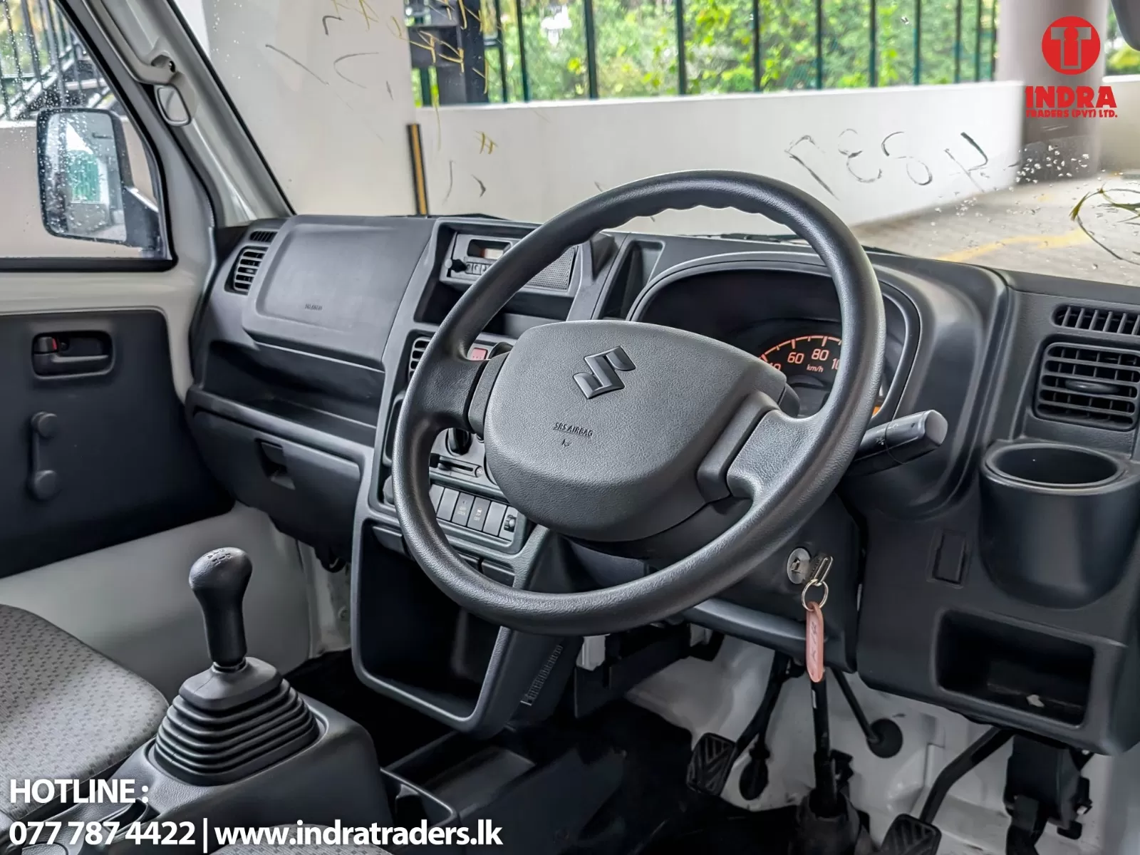 Interior view of a right-hand drive vehicle dashboard with steering wheel, gear stick, and driver-side door; clear view of the instrument cluster and center console.