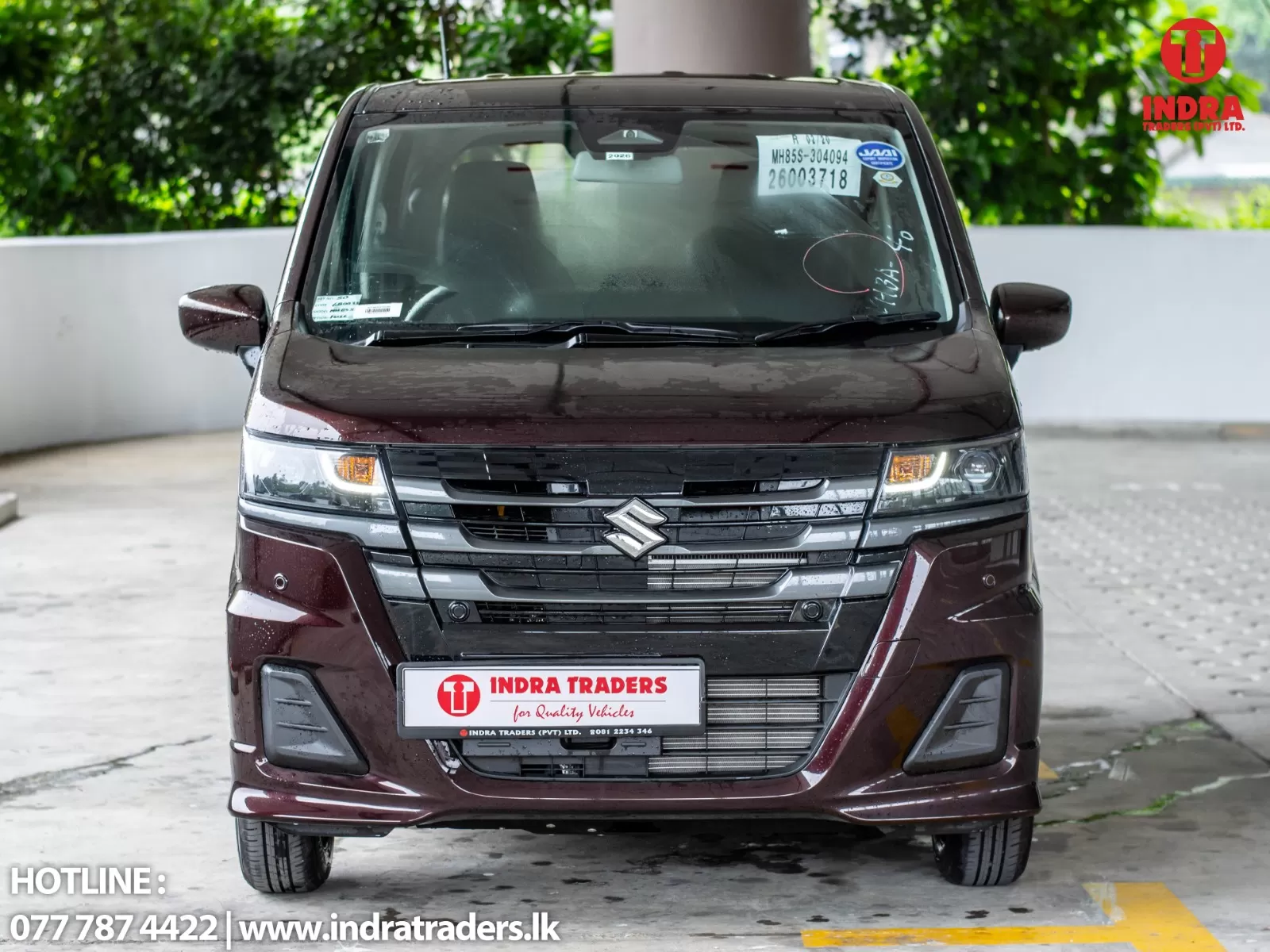 Front view of a maroon Suzuki van with Indra Traders license plate in a parking area.
