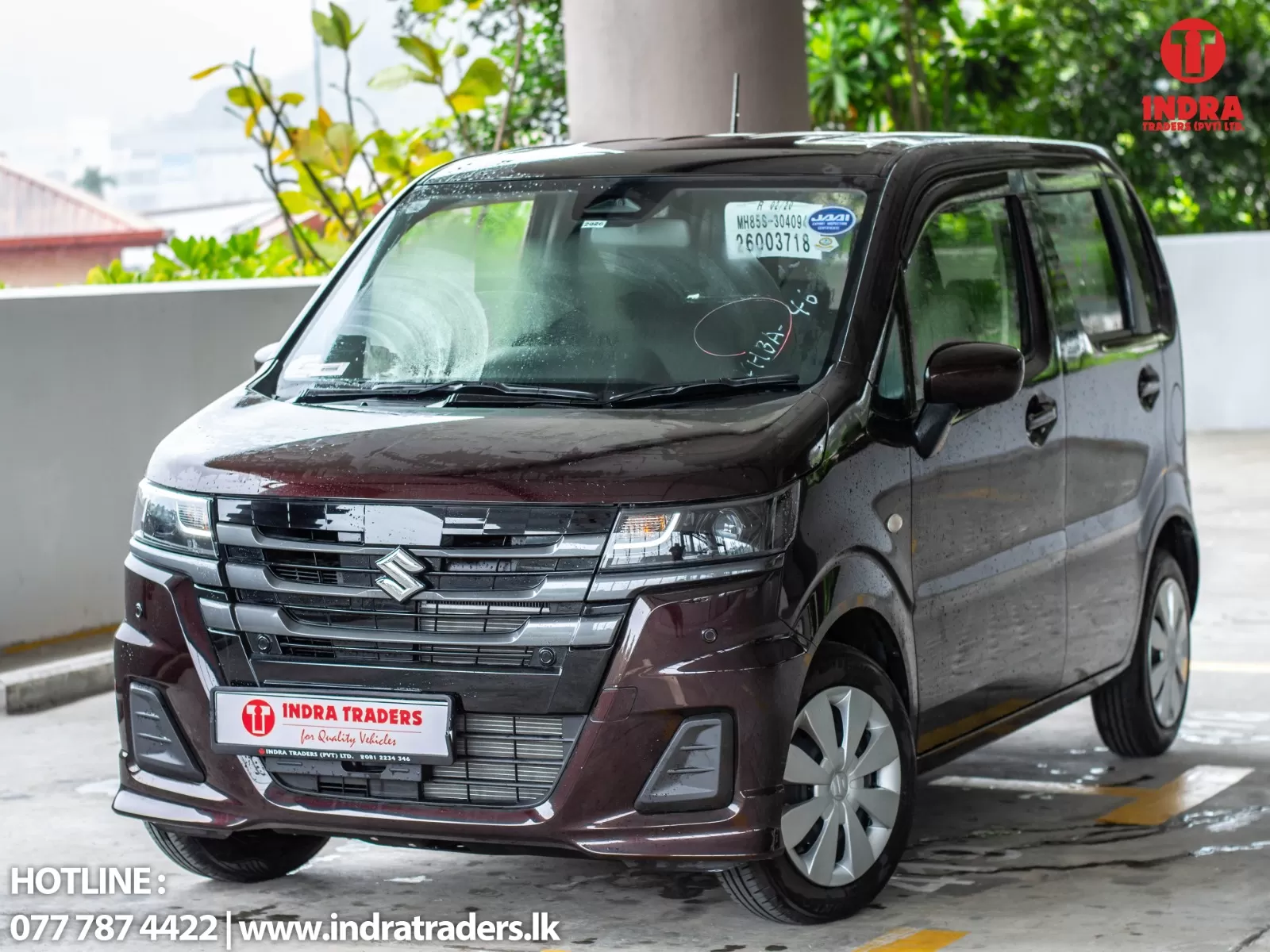 Maroon Suzuki minivan parked in a dealership lot, front grille prominent and Indra Traders branding visible on the scene corner and windshield stickers.