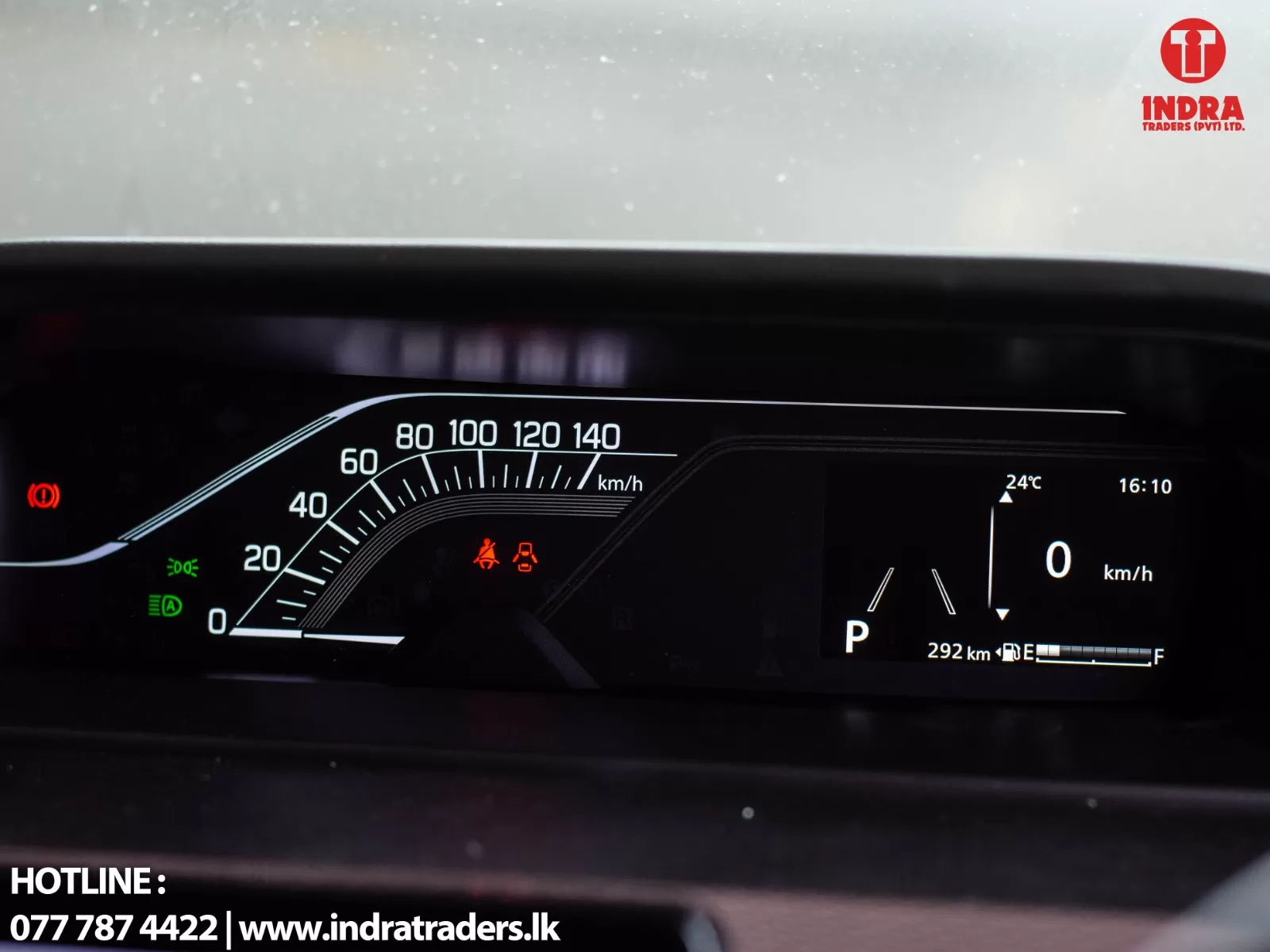 Car dashboard display: speedometer up to 140 km/h, digital panel shows 0 km/h, gear in P, time 16:10, temp 24°C, range 292 km, fuel bar visible, Indra watermark top-right.