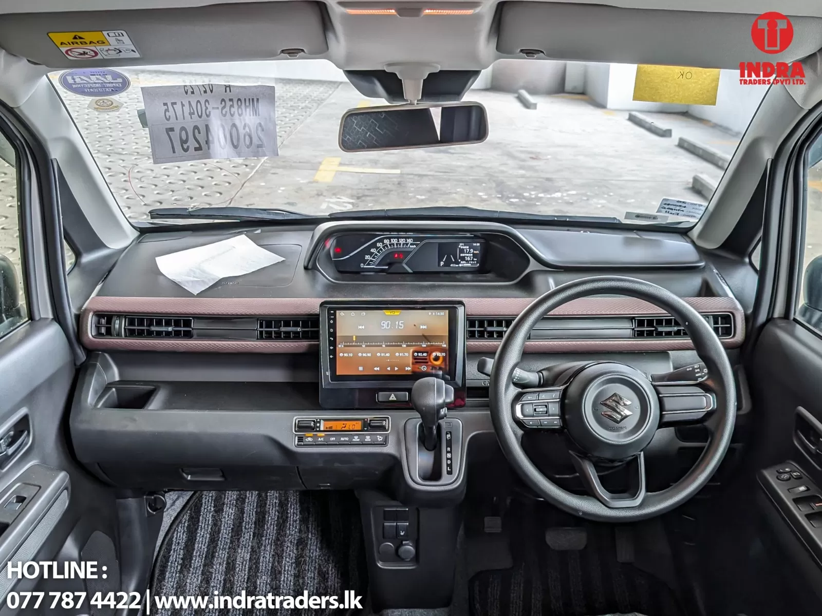 Front interior of a car showing steering wheel, digital instrument cluster, and a central touchscreen infotainment system.