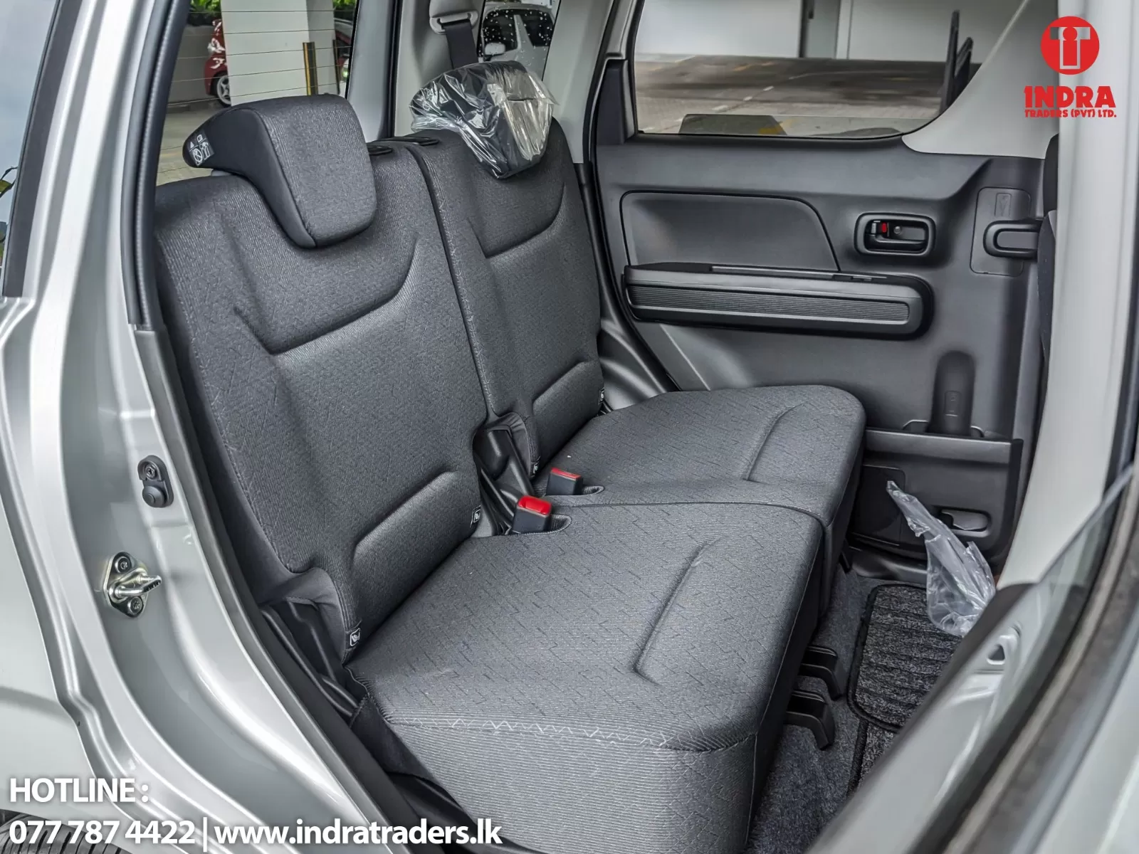 Rear bench seat in a gray car interior, with headrests and red seat belt buckles visible on the seats.