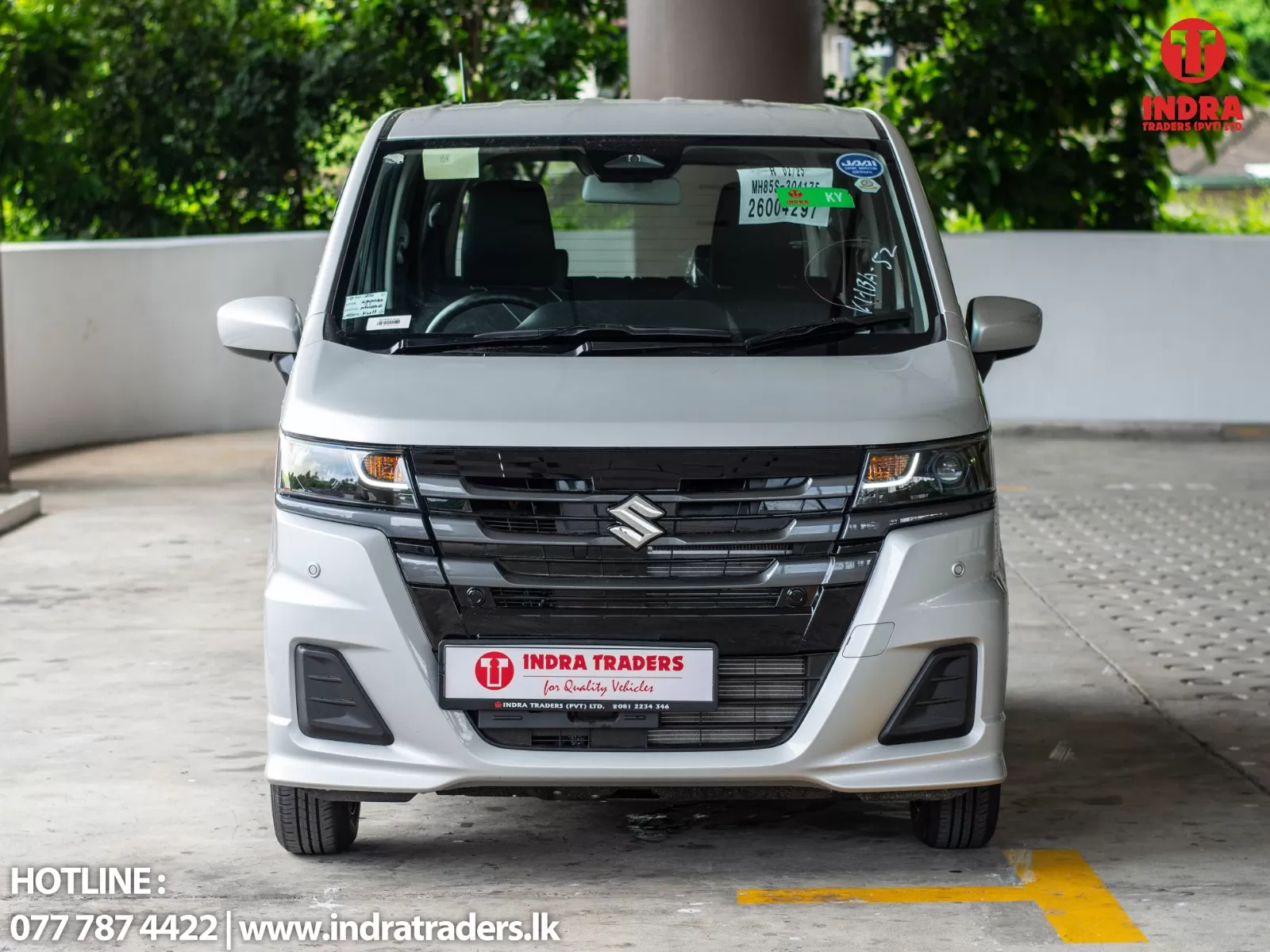 Front view of a silver Suzuki van in a dealership lot, with Indra Traders branding on the windshield and license-plate area visible.