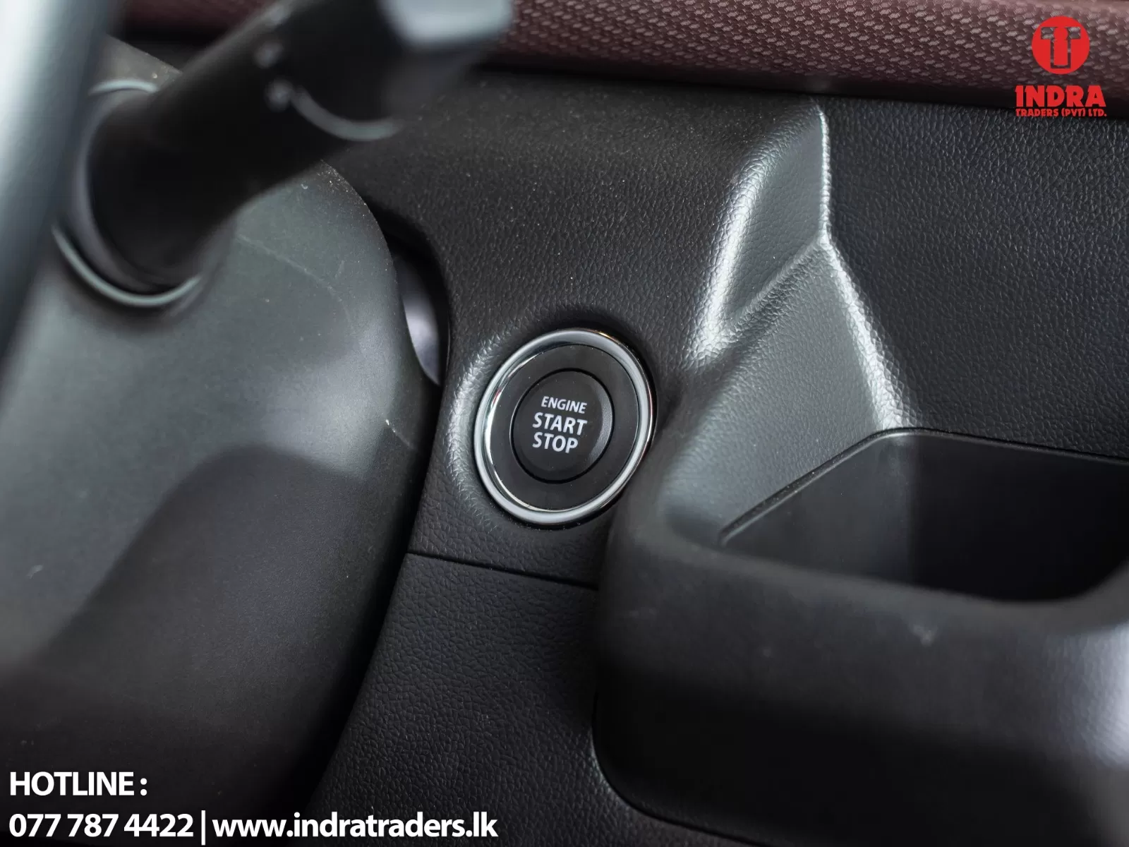 Close-up of a car engine start/stop button surrounded by a chrome ring on a black textured dashboard.