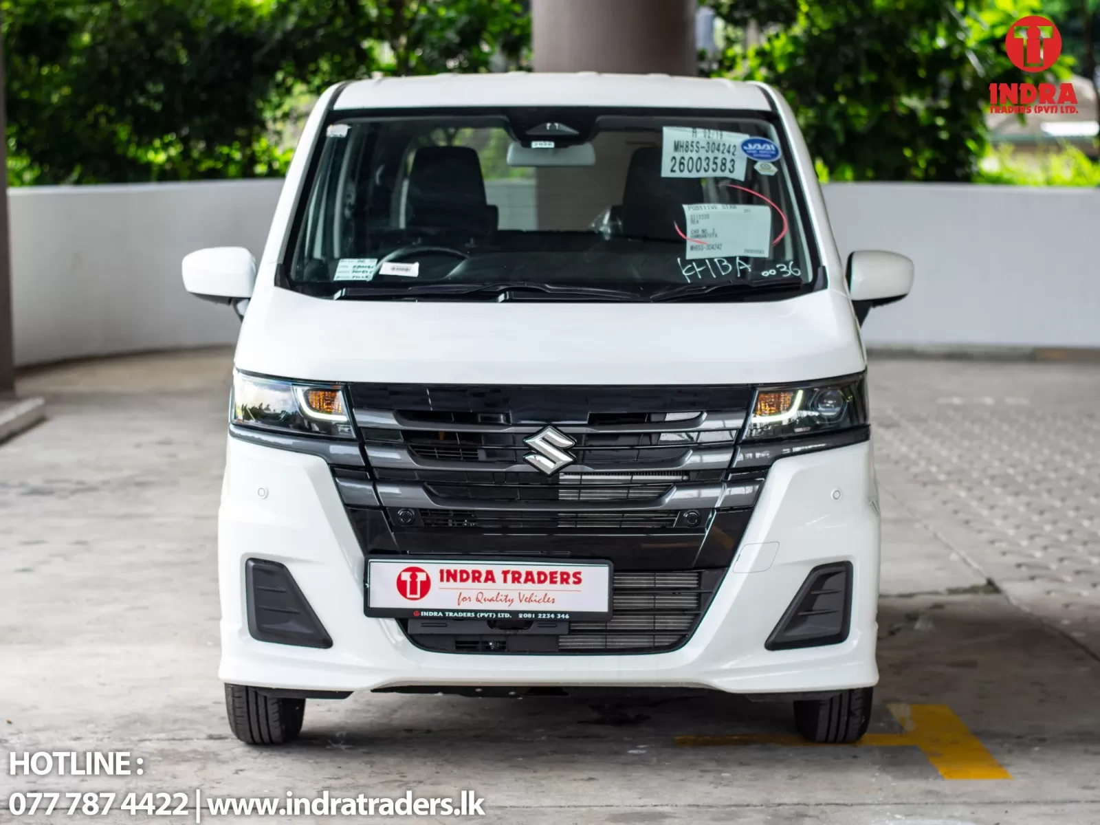 Front view of a white Suzuki van parked in a lot, with Indra Traders branding on the front and a dealership license plate area visible at center.