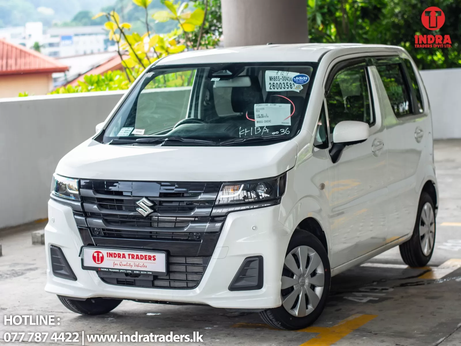 White minivan labeled Indra Traders, parked in a lot with the hotline text visible at the bottom left edge.