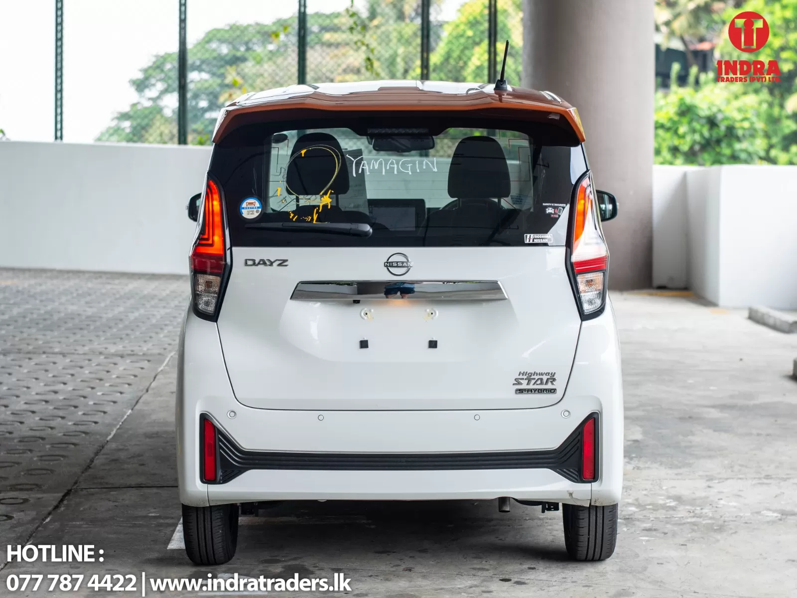 Rear view of a white Nissan Dayz SUV parked in a covered area; showroom-like branding and contact info visible.