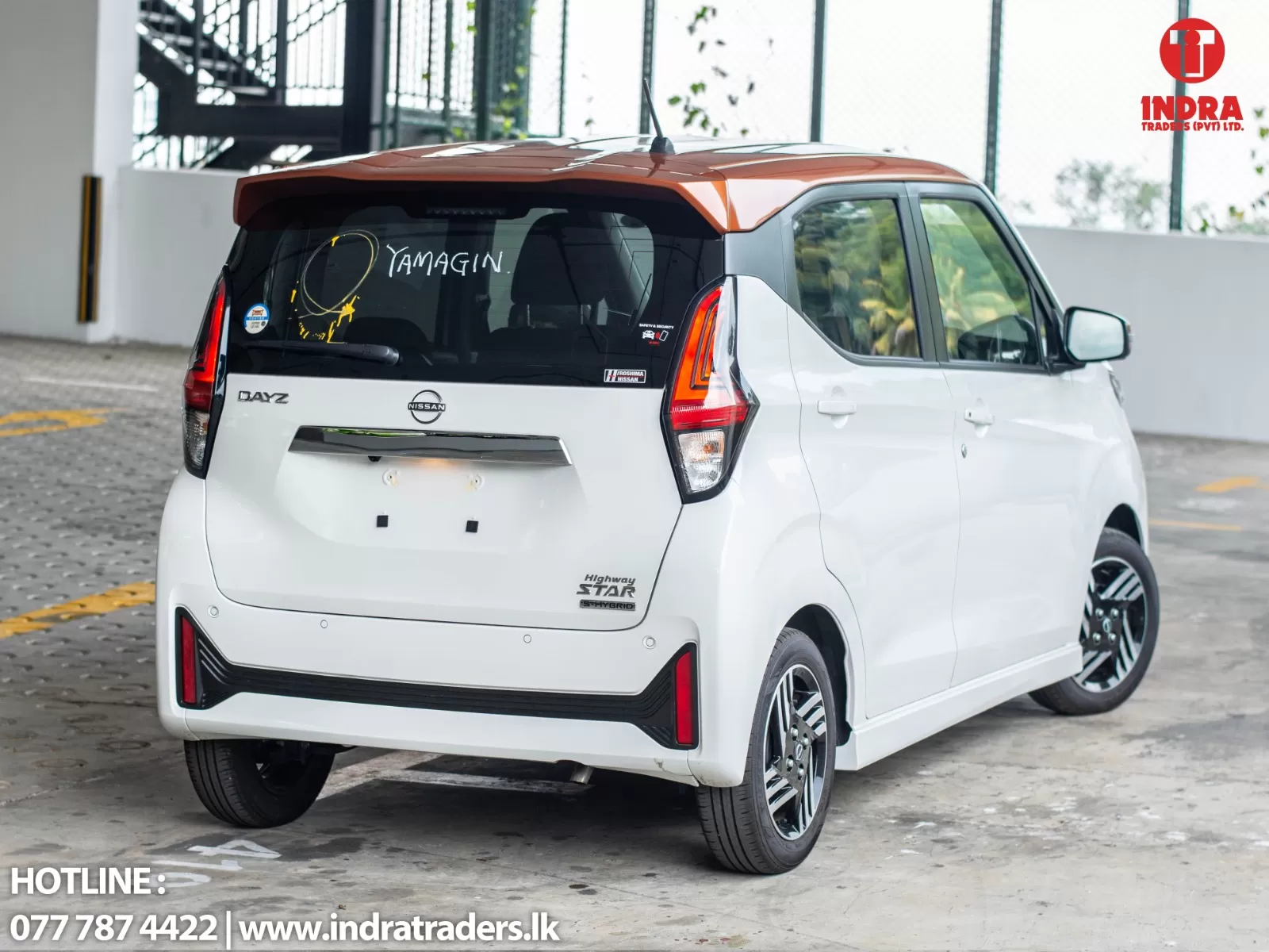 White Nissan Dayz compact hatchback parked in a lot, with Indra Traders branding in the corner and contact text at the bottom left.