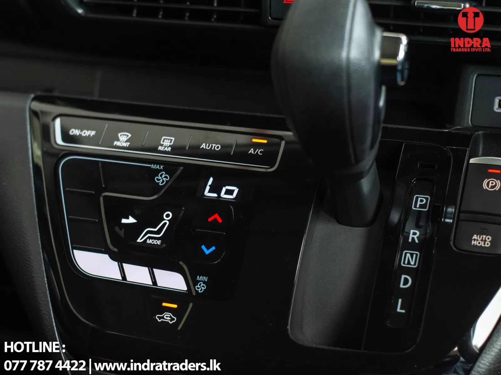 Close-up of a car center console showing climate controls and the gear selector, with the Indra Traders logo in the top-right.