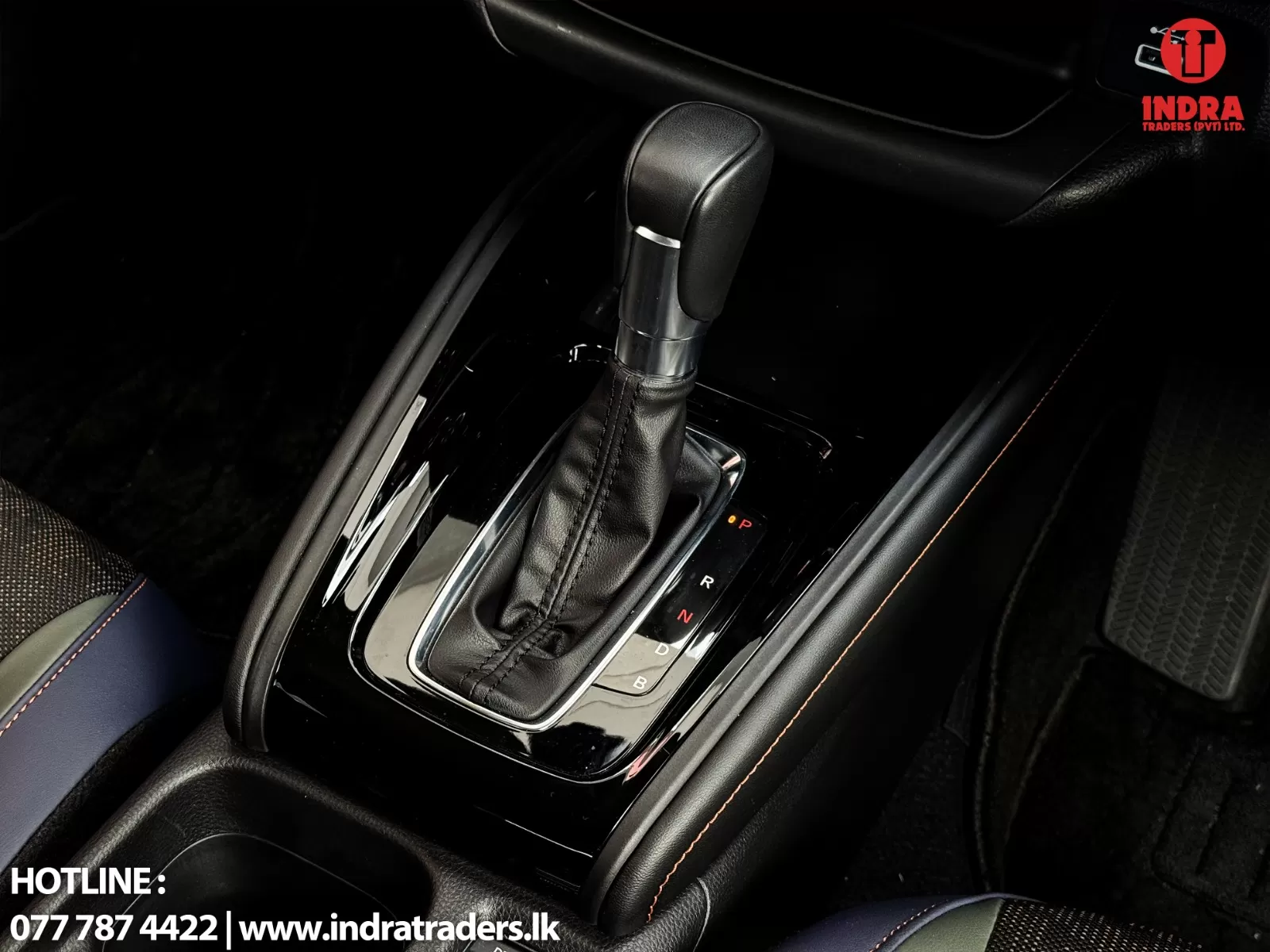 Automatic gear selector in a car, with leather boot and glossy center console around the shift indicator (P R N D).