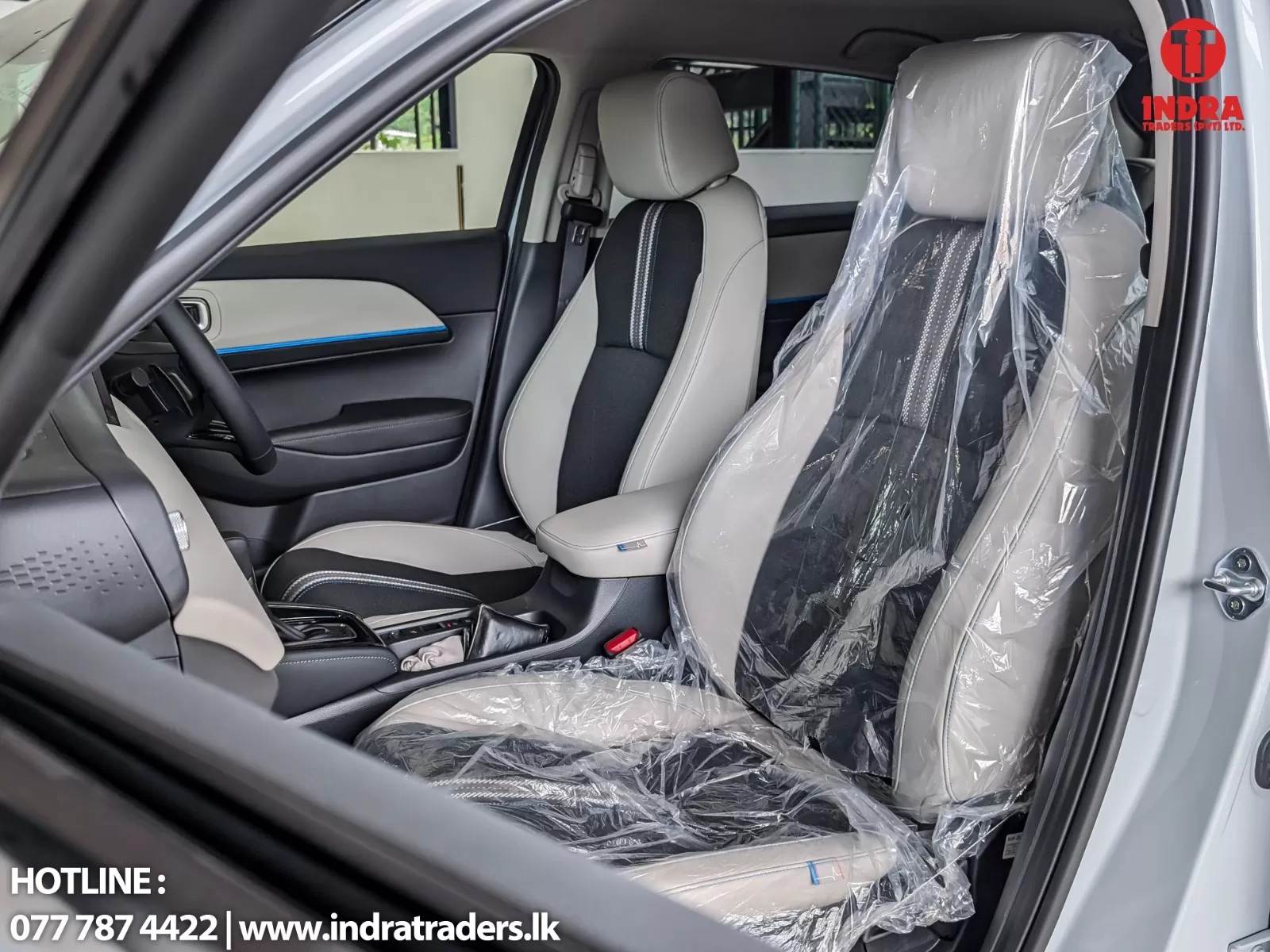 Front interior of a new SUV with plastic-covered seats, gray and black upholstery, and a center console edge visible.