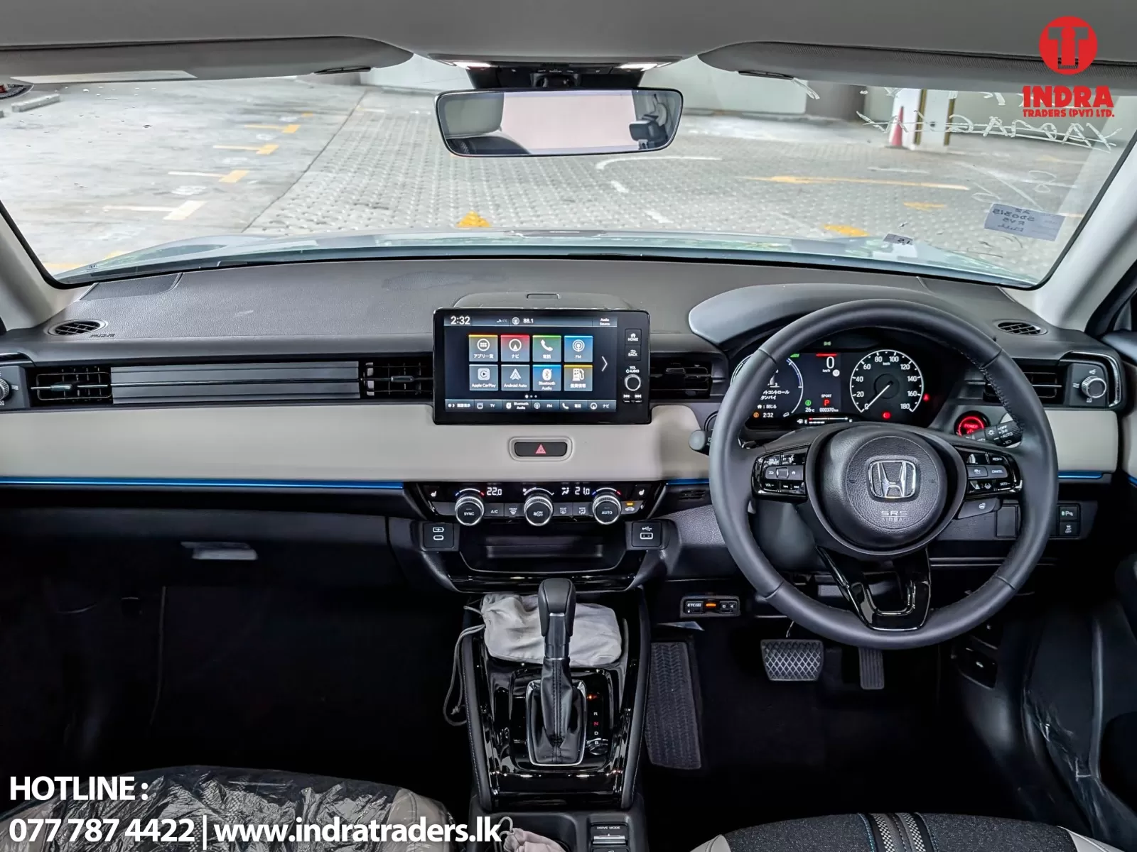 Front cockpit of a car showing a large center touchscreen, digital instrument cluster, steering wheel, and gear shifter.