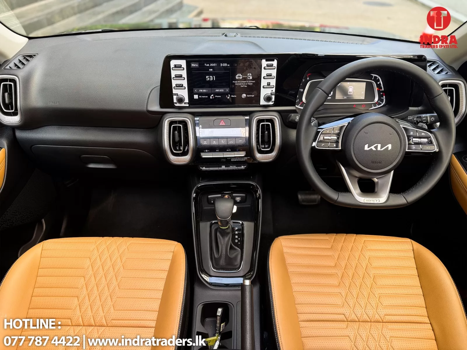 Interior of a modern car showing a wide touchscreen infotainment system, steering wheel, center console, and tan perforated seats