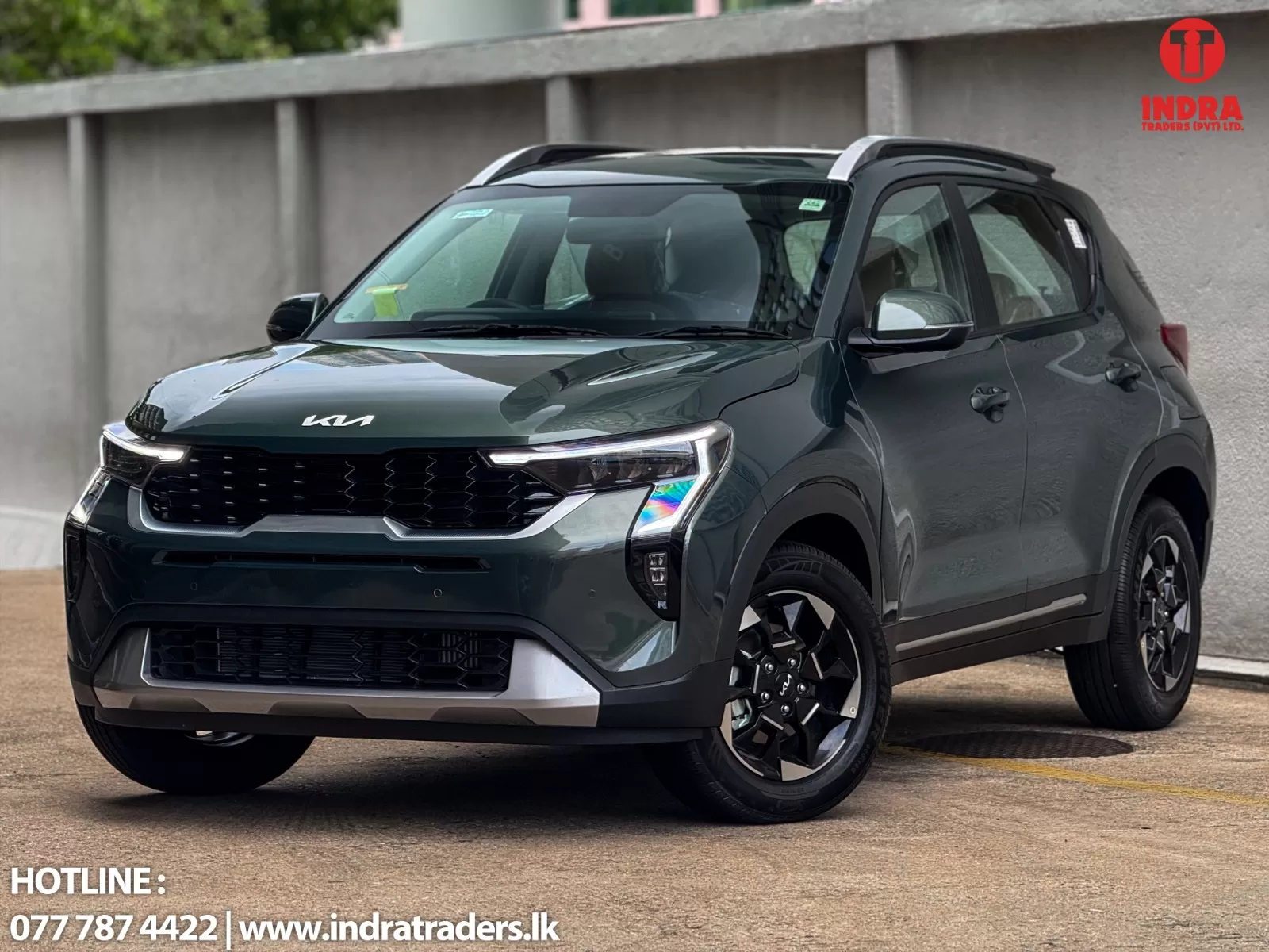 Green Kia SUV angled in a parking lot with Indra Traders logo top-right and contact info at bottom-left.