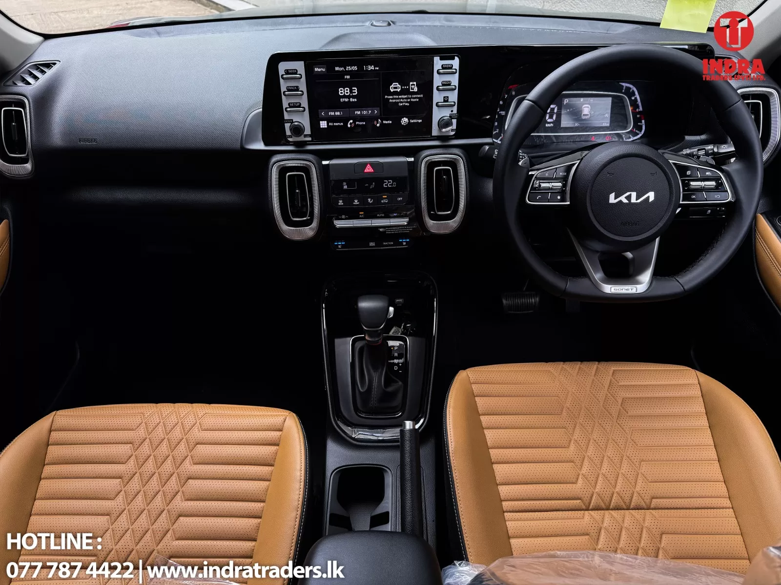 Interior of a Kia car with tan quilted leather seats, black dashboard, center touchscreen, steering wheel, and gear shifter; dealership watermark in lower-left.