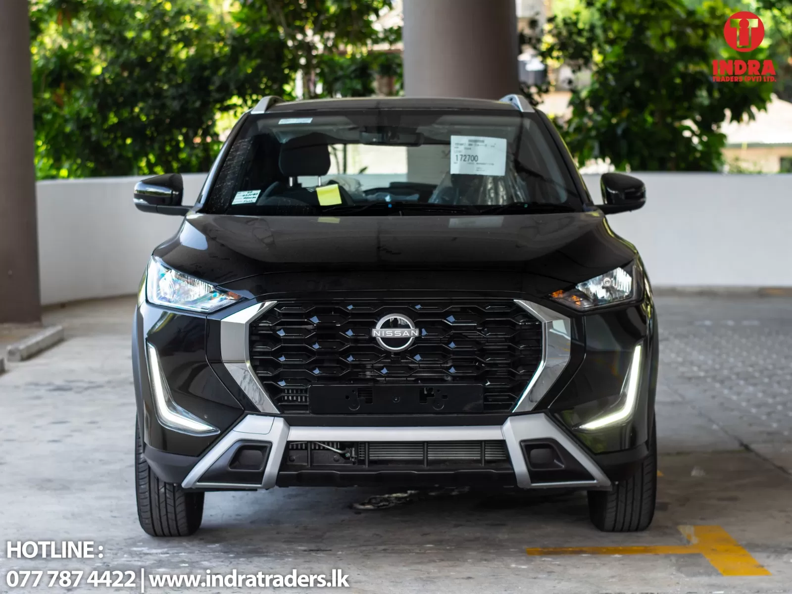 Front view of a black Nissan SUV parked indoors, showing the grille and headlights with a dealership watermark in the top-right corner.