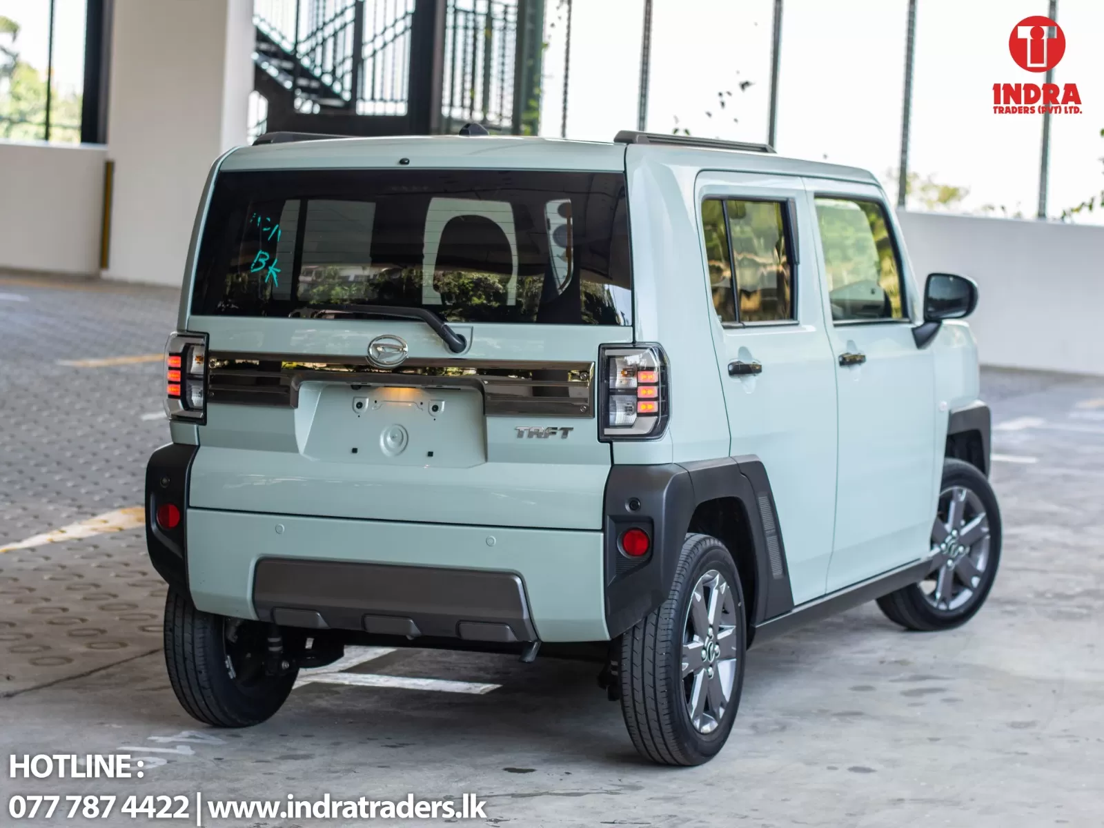 Rear three-quarter view of a light-blue Daihatsu Taft SUV in a parking lot, Indra Traders logo in the top-right corner.