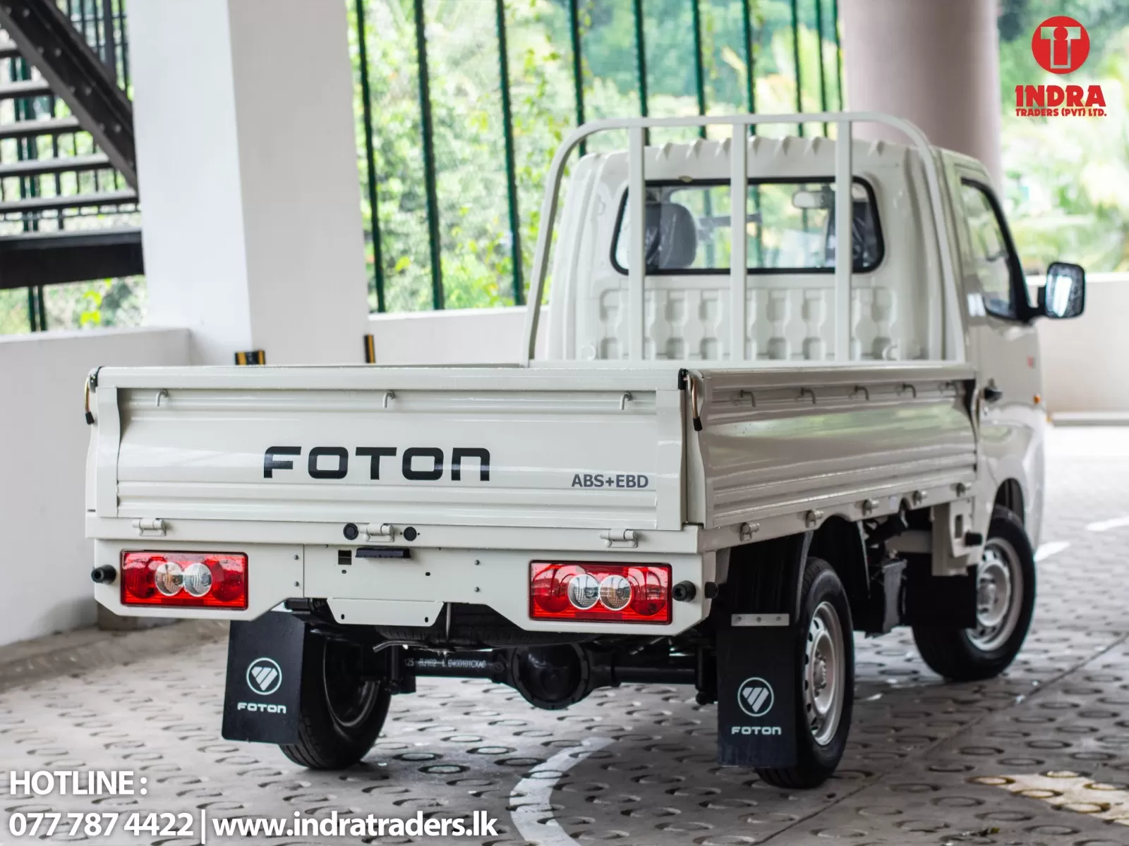 White FOTON pickup truck with branding, parked under a covered area; Indra Traders logo in the top-right and contact info at bottom-left.