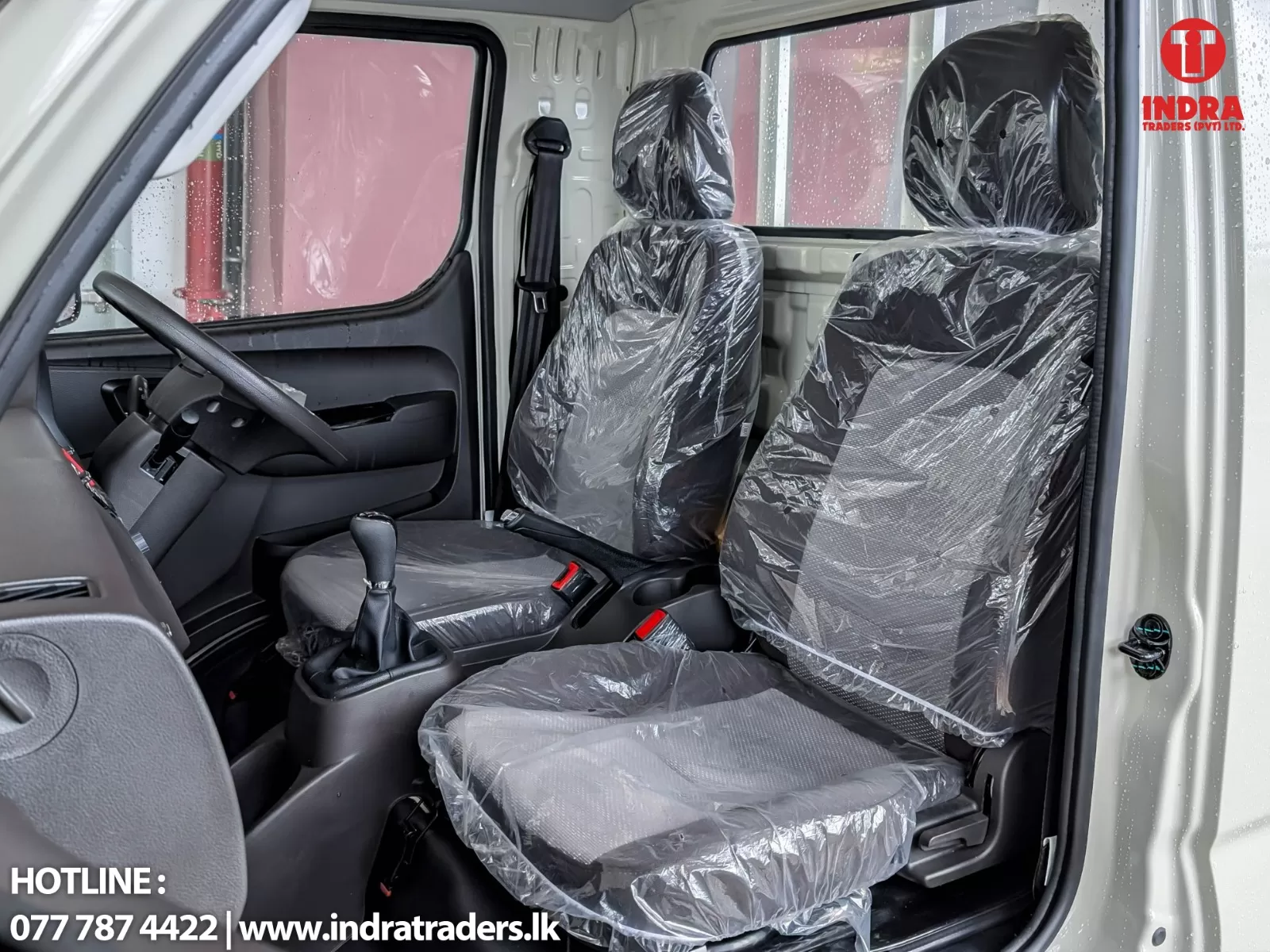 Interior of a new van with plastic-wrapped front seats, steering wheel, and gear shifter visible.