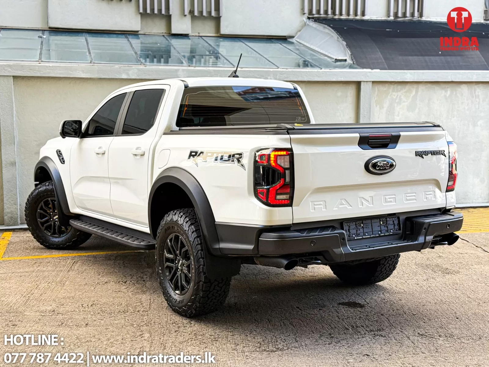 White Ford Ranger Raptor pickup parked outdoors, with Indra Traders logo in the top-right corner and contact info visible at the bottom-left.