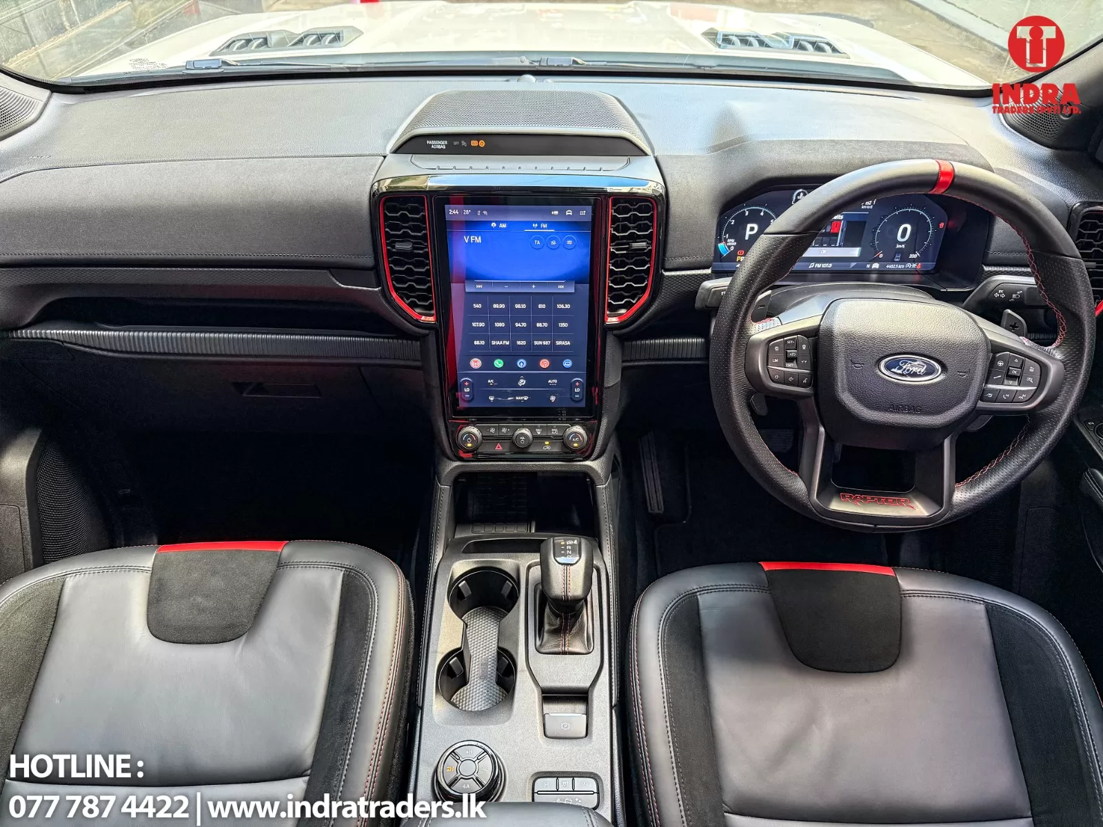 Interior of a Ford vehicle with a tall vertical touchscreen in the center, digital driver display, and black leather seats with red stitching.