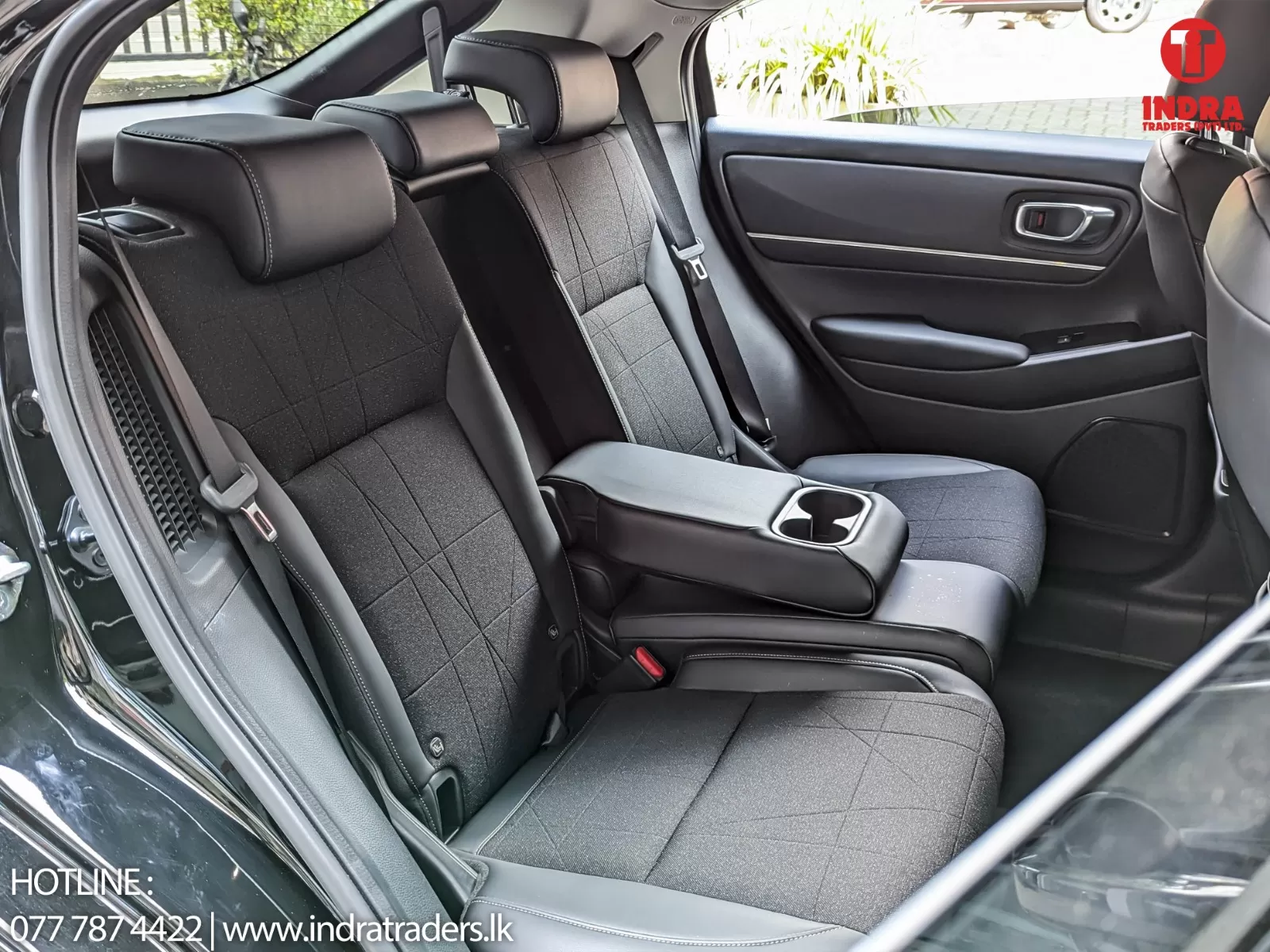 Rear seats of a black car with three headrests, center armrest folded down showing cup holders, dark fabric upholstery
