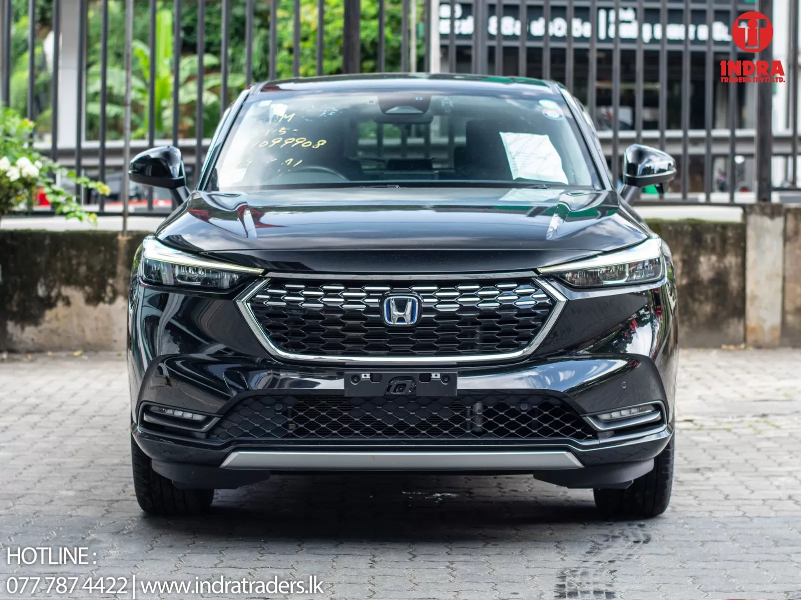 Front view of a black Honda SUV, showing grille and headlights, with dealer branding in the top right and contact text in the bottom left.
