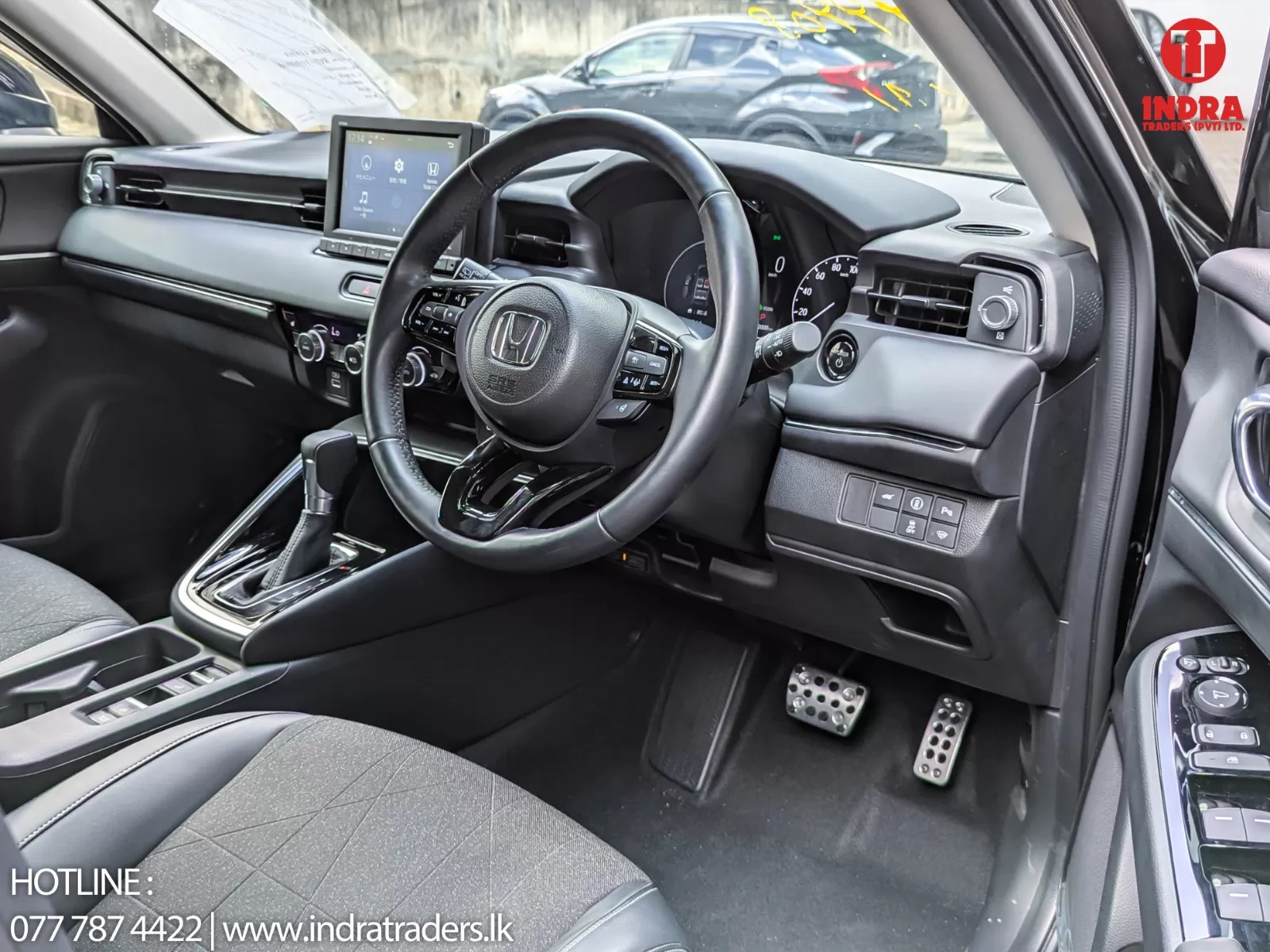 Driver’s cockpit of a Honda car featuring a touchscreen infotainment system, steering wheel, and gear shifter.