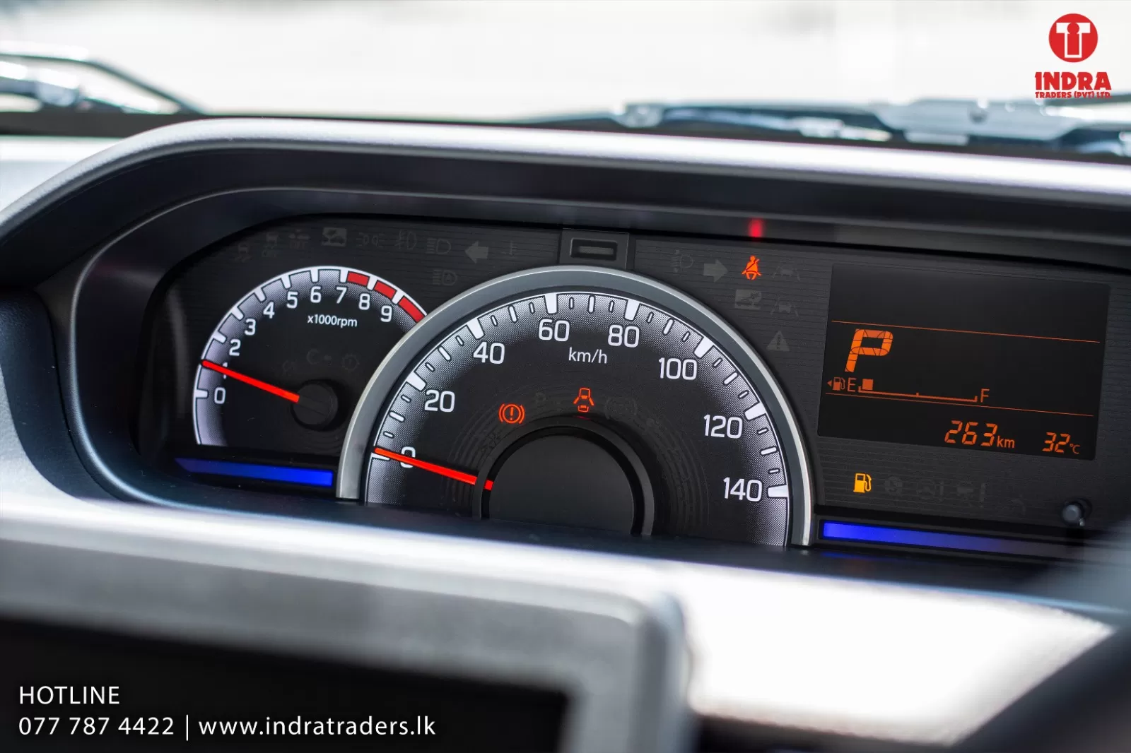 Close-up of a car instrument cluster showing the speedometer (0–140 km/h), tachometer, warning lights, and a right-side digital display with gear indicator and fuel info.