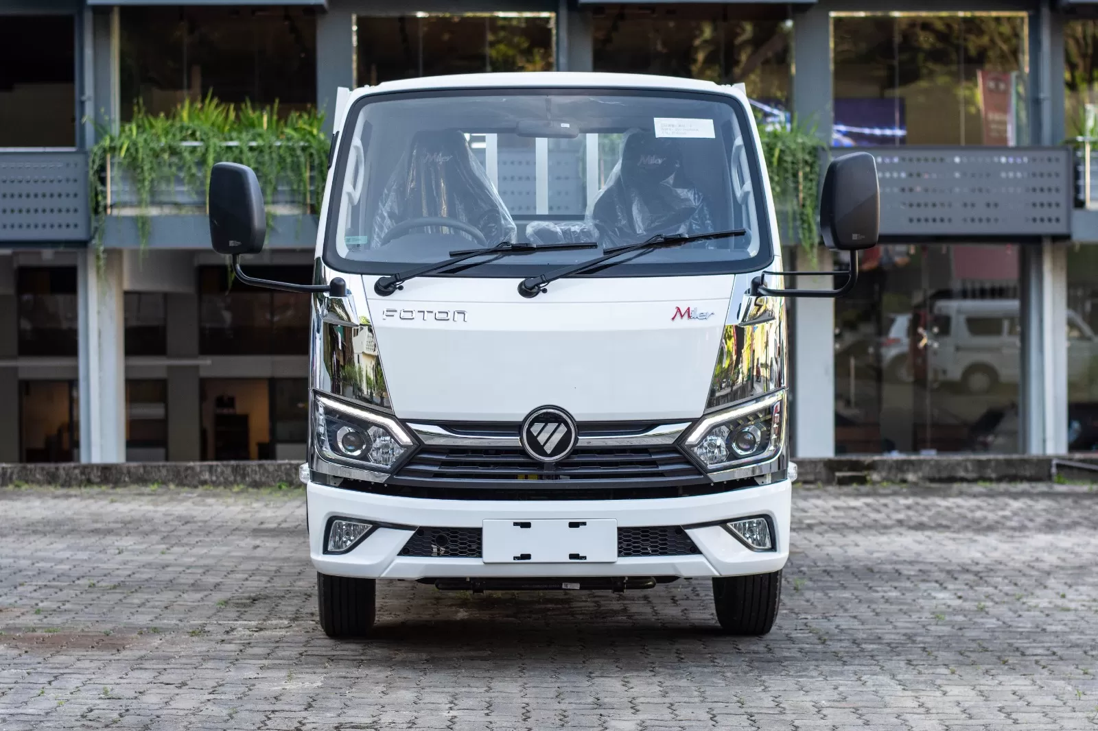 Front view of a white Foton truck parked on a paved lot, large side mirrors extended.