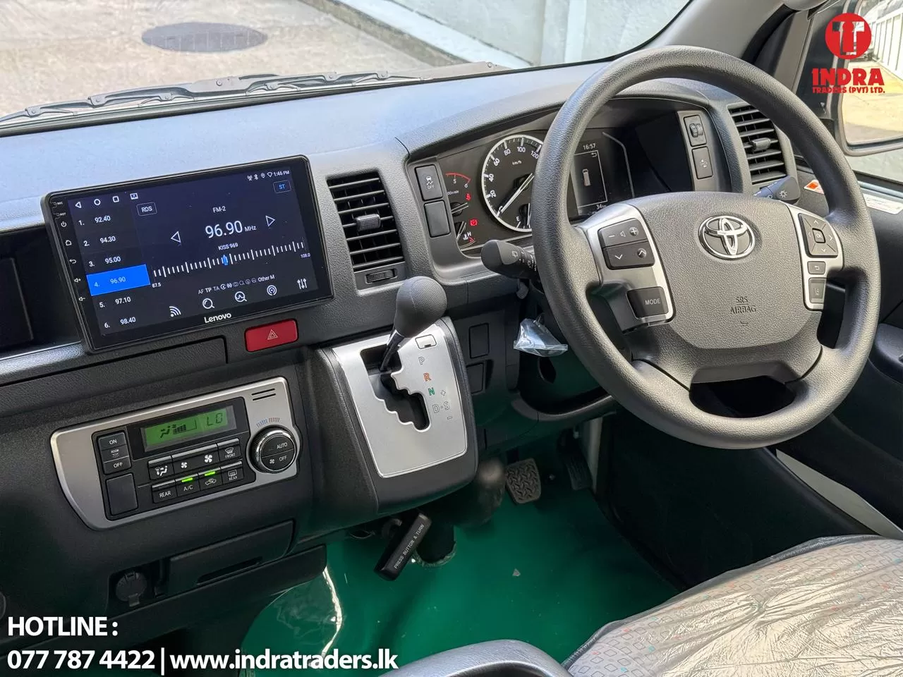 Interior view of a vehicle dashboard: steering wheel with controls, large touchscreen displaying radio 96.90 MHz, and climate controls nearby.