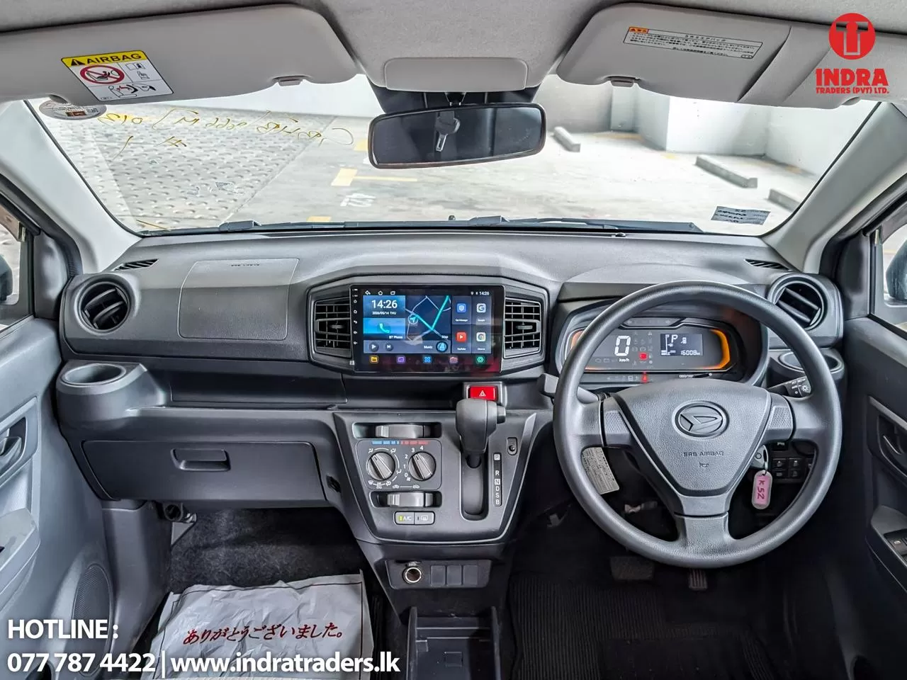 Interior of a right-hand-drive car, showing steering wheel, digital instrument cluster, and a central touchscreen with climate controls below it.