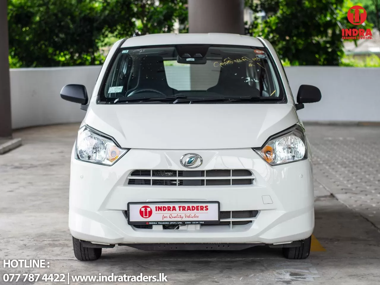 Front view of a white car with an Indra Traders license plate, photographed at a dealership.